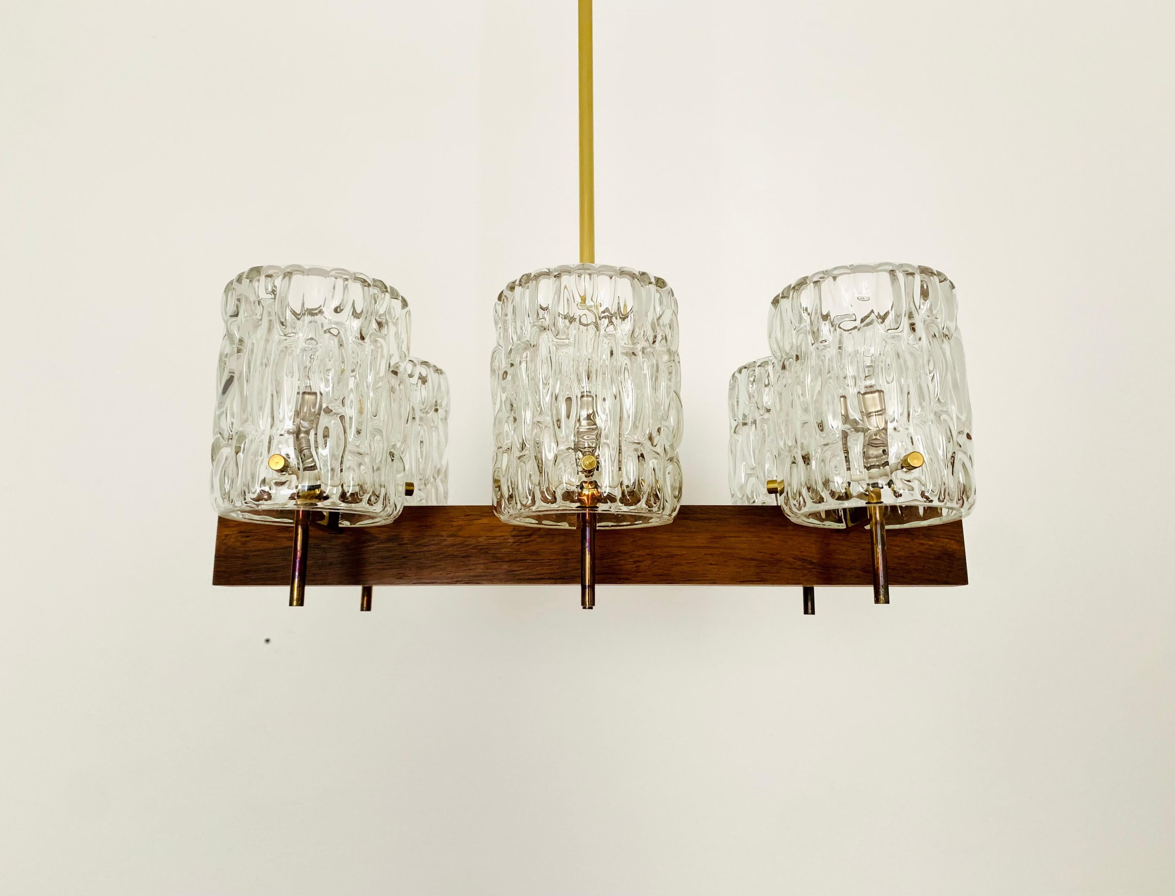 Breathtakingly beautiful crystal glass chandelier from the 1950s.
Wonderful mouth-blown glass with a great structure.
The wood underlines the elegant appearance.
The design and the materials used create a great glittering light.
An enrichment for