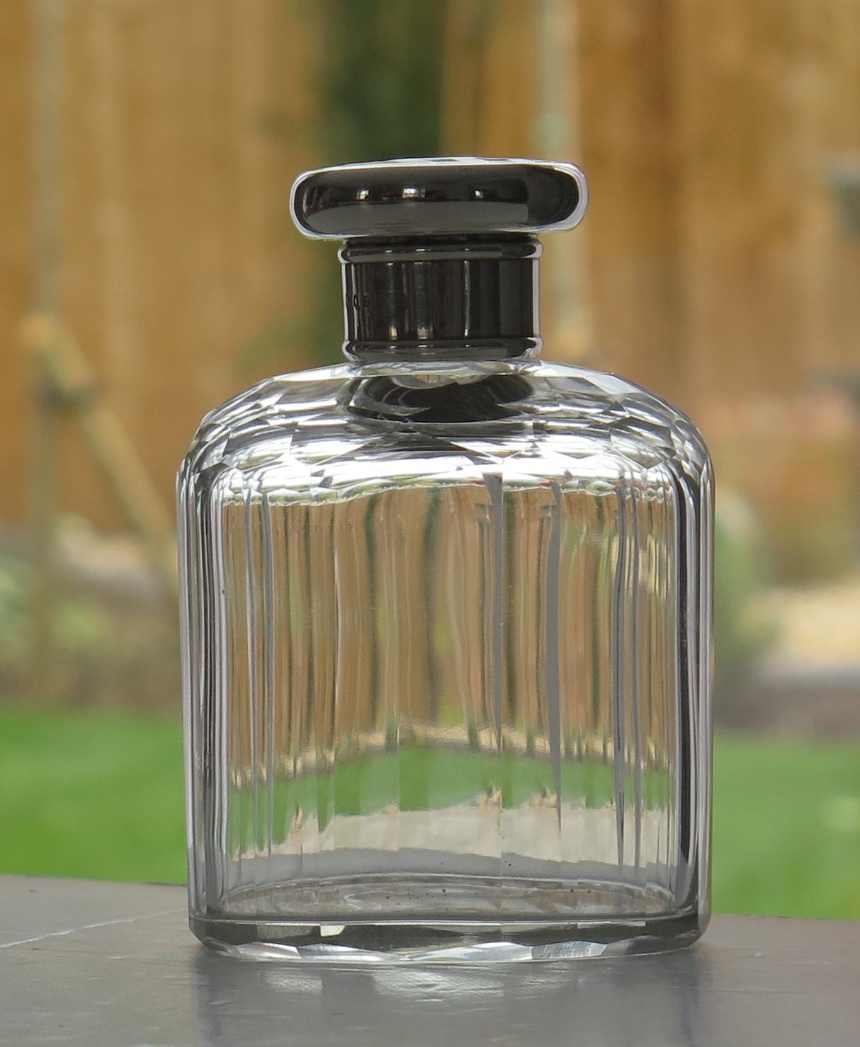 This is a very good quality crystal cut glass cologne or perfume bottle with a sterling silver screw top lid, made in London and dating to the early Art Deco period, 1919.

The clear glass bottle or jar has a rectilinear shape, having an oval
