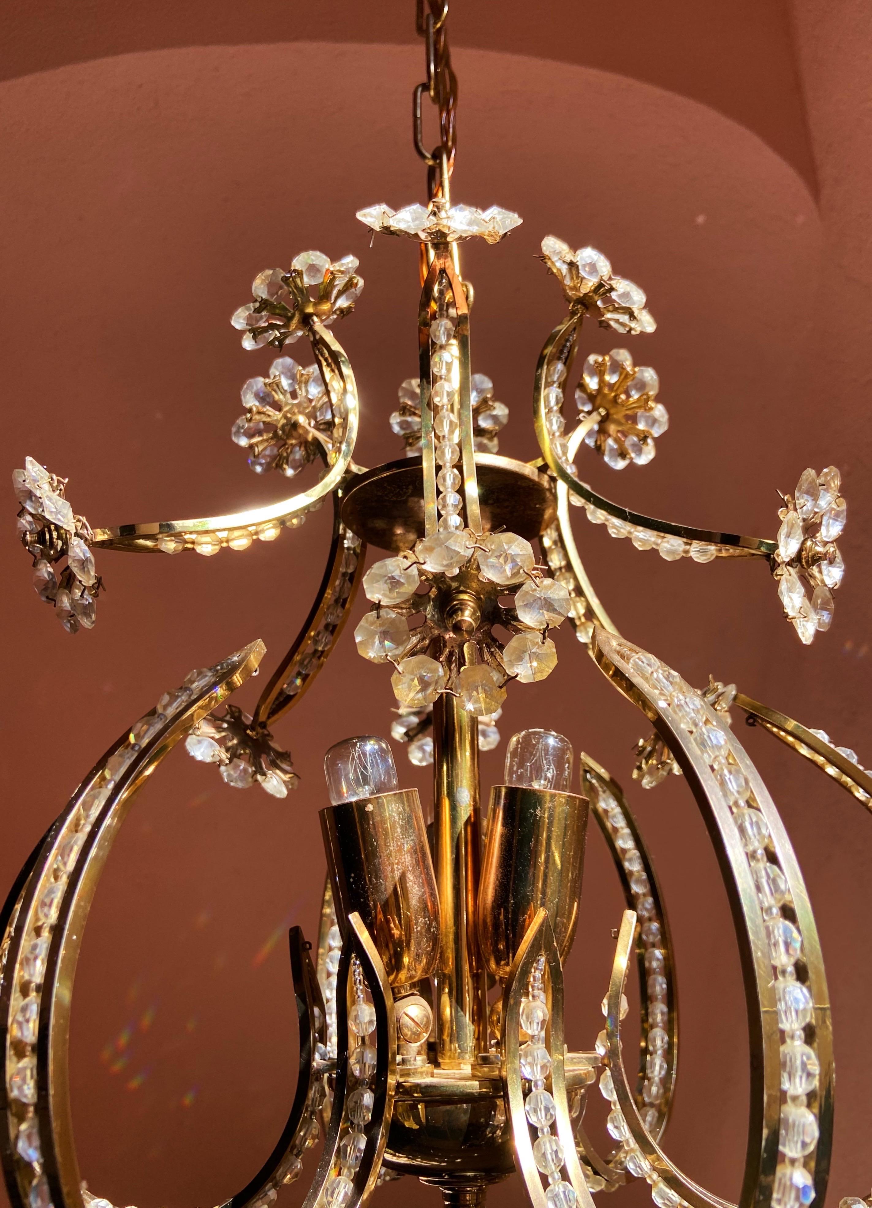 Chandelier by Palwa, 1960. It features a gold-plated brass frame with crystal prisms and beads.

Details
Creator: Palwa
Dimensions: Height: 35 cm Height with chain: 85 cm Diameter: 33 cm
Materials and Techniques: Chrome, brass, crystal,
