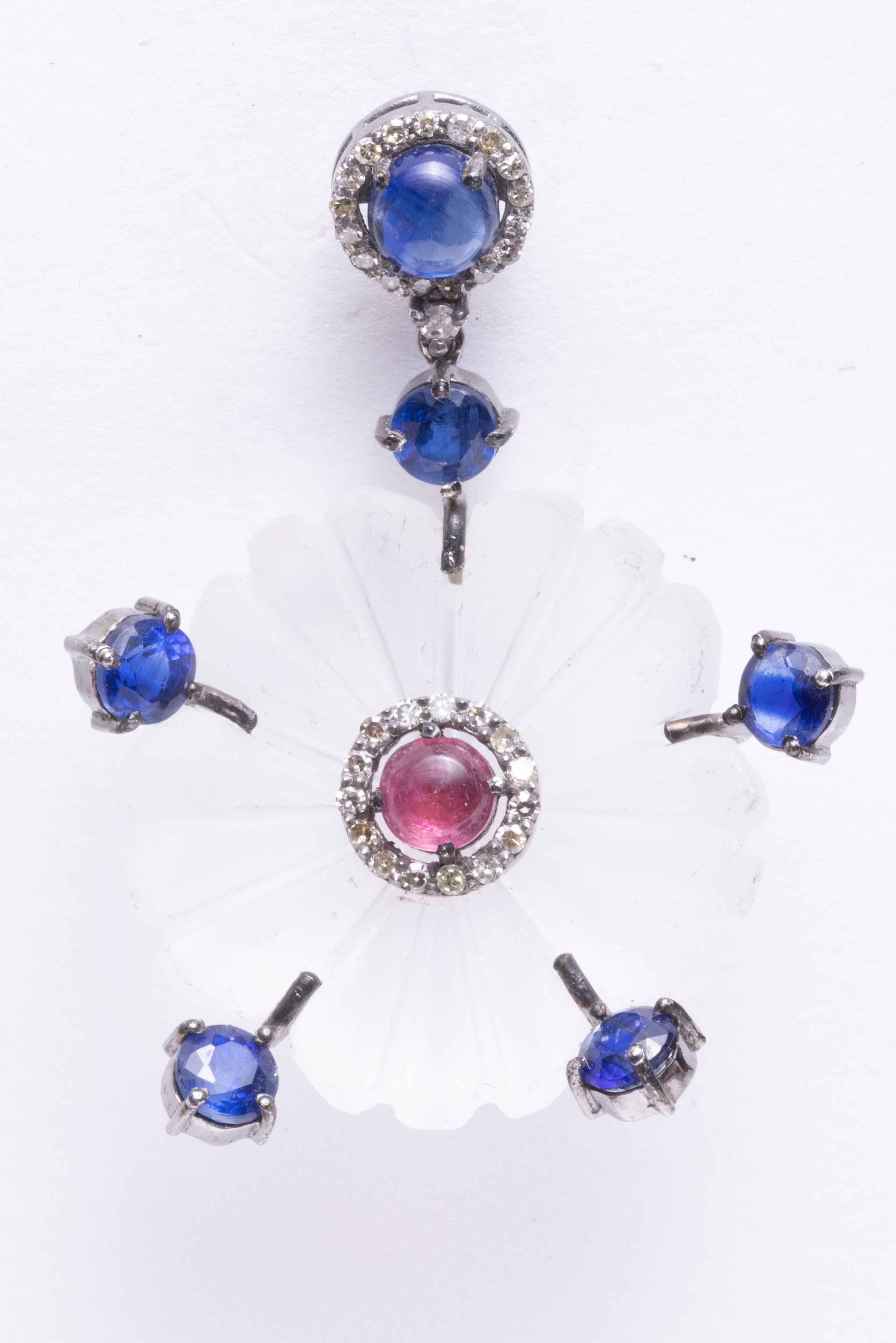 An unusual pair of carved crystal earrings in a floral motif.  Features a cabochon pink tourmaline center bordered with round, faceted diamonds.  Blue kyanite stones radiate out to the edges and also on the post which is again bordered with