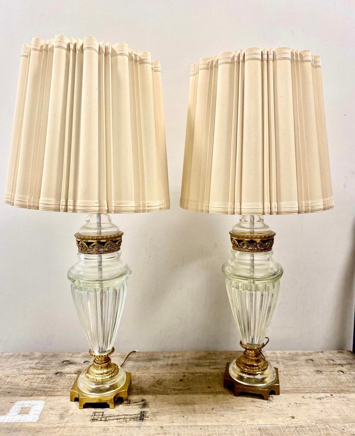 Mesmerizing Murano crystal lamp with deep vertical ribs and ornate brass adornments. The thick high quality cystal has a deep rich glow when lit.
Each surmounted by the original cylindrical pleated shade, the body of baluster form is 20’ with brass