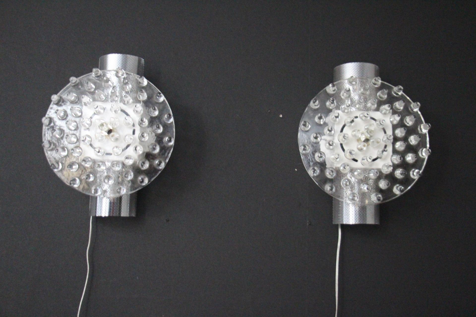 Questa sorprendente coppia di lampade da parete è composta da un disco di vetro di Murano bianco e cristallino lavorato con punte di vetro, inserito in una lastra d'argento testurizzata per produrre questo effetto eccezionale. Quest'opera d'arte