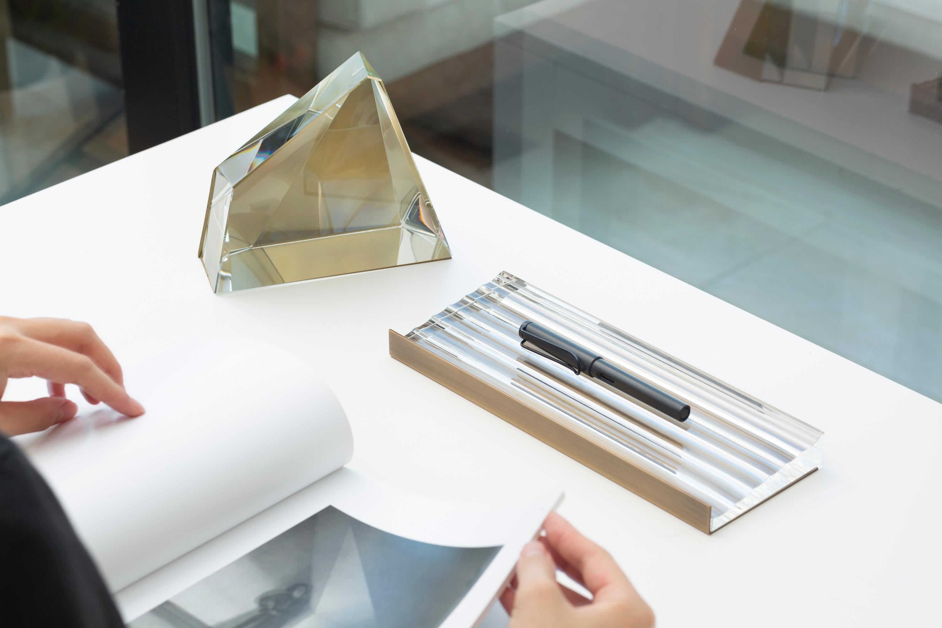 Eleva tu espacio de trabajo con la elegante bandeja para bolígrafos Crystal. Este moderno accesorio de escritorio presenta una sofisticada combinación de cristal transparente y detalles de latón, ofreciendo un aspecto minimalista pero distintivo.