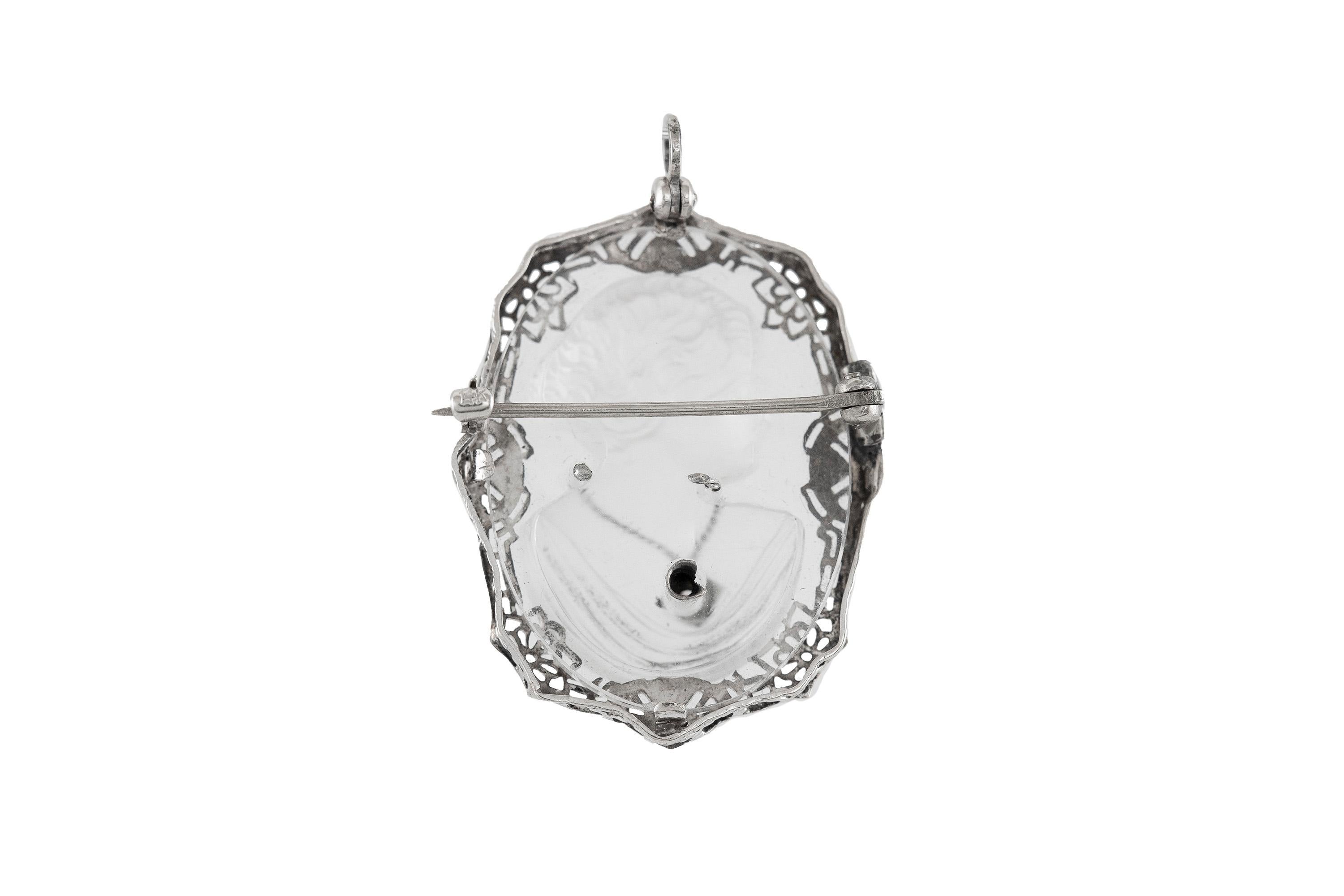 Oval pendant finely crafted in 14k white gold and crystal, with a diamond weighing a total of 0.50 dwt, which is worn by a lady. Circa 1920.