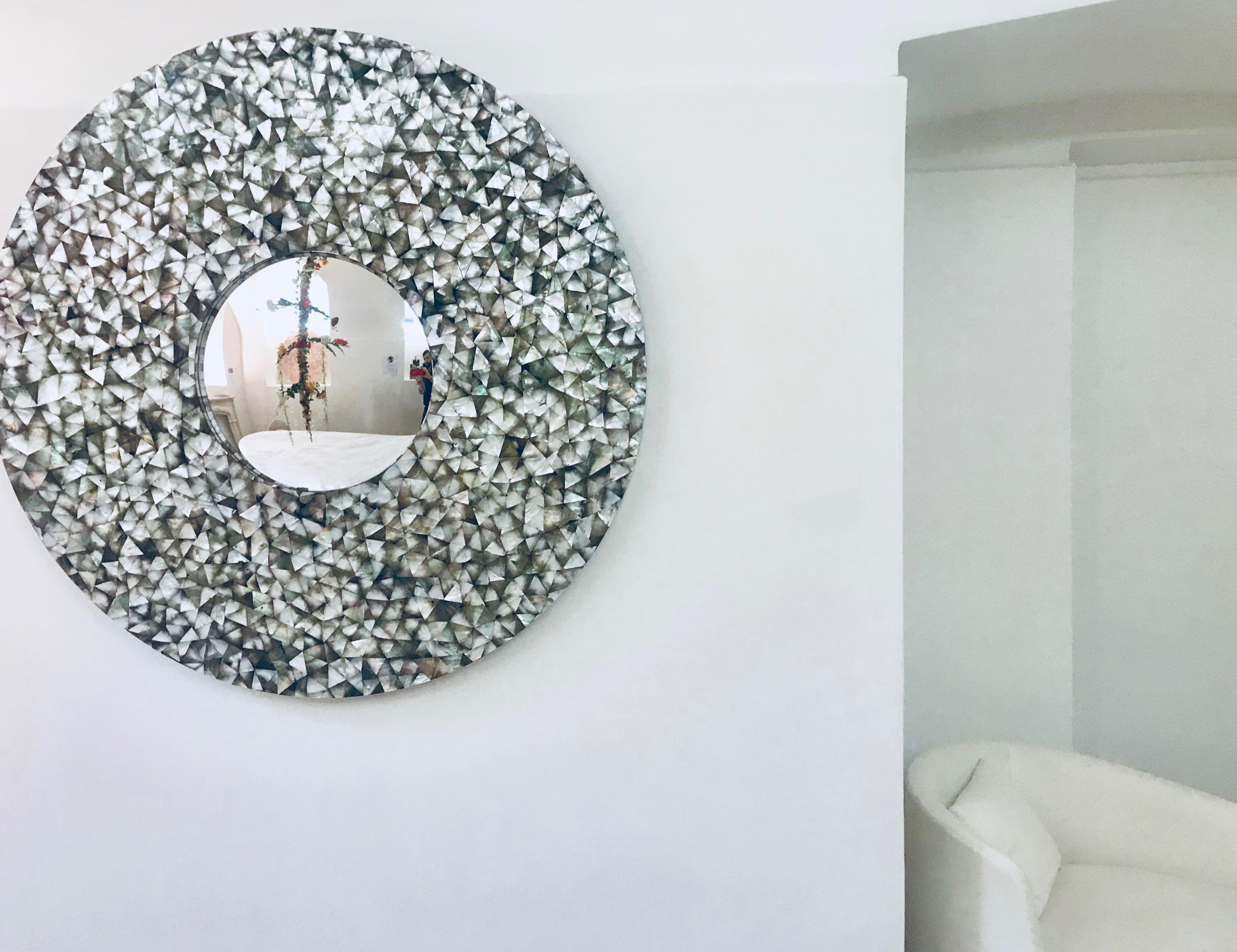The 'Crystal Sea' is a large handcrafted wall mounted piece with a convex central mirror which amplifies its surroundings.

Its frame is inlaid with hundreds of pieces of irrgegularly cut Mother of Pearl. Mother of Pearl an authentic jewel of the