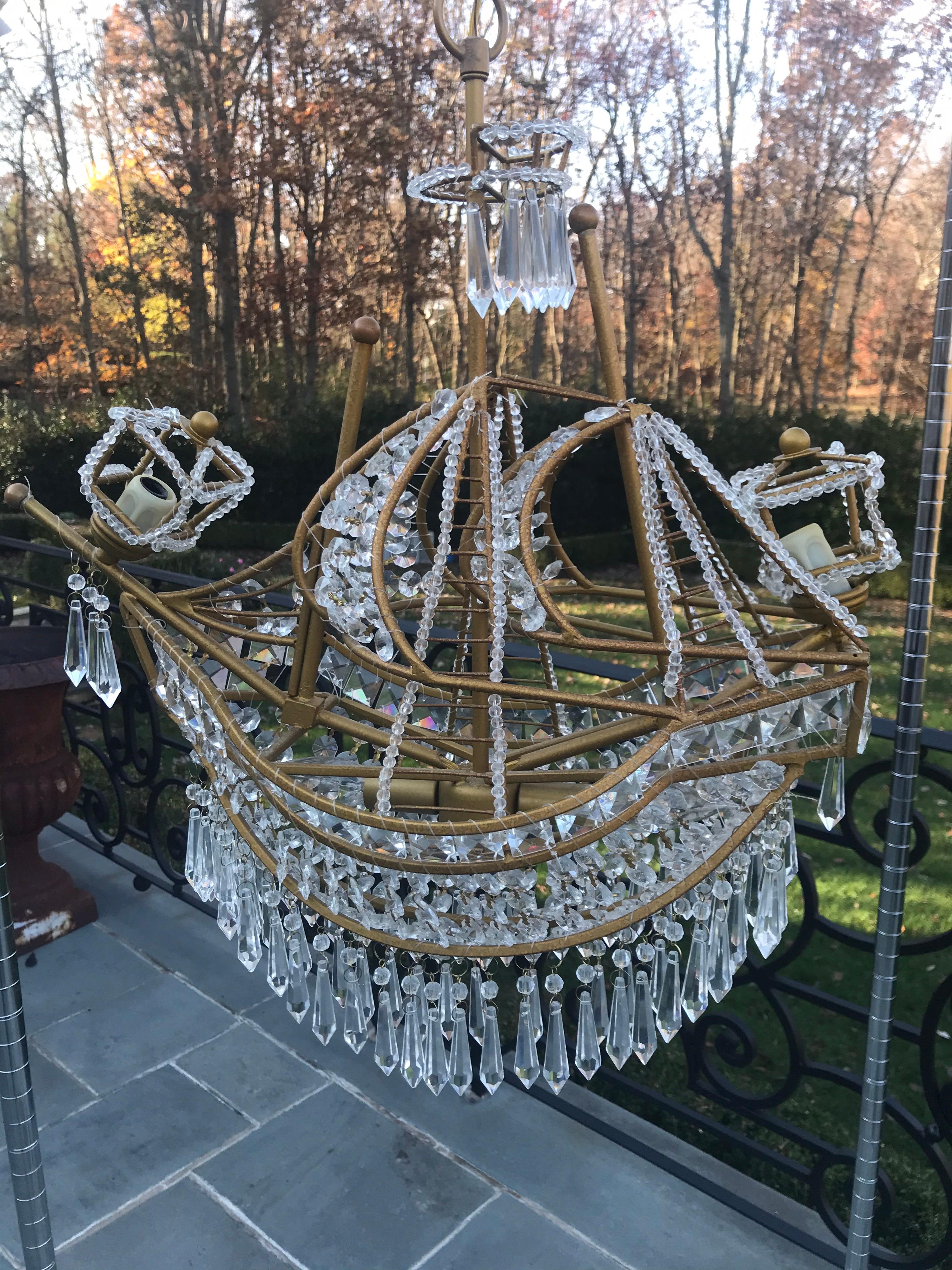 Uniquely extravagant, this crystal ship chandelier layers your decor with glimmering light and unique detailing. This crystal ship chandelier exudes style and grace. Adorned with sparkling crystal glass pieces in the outline of a antique gold ship,