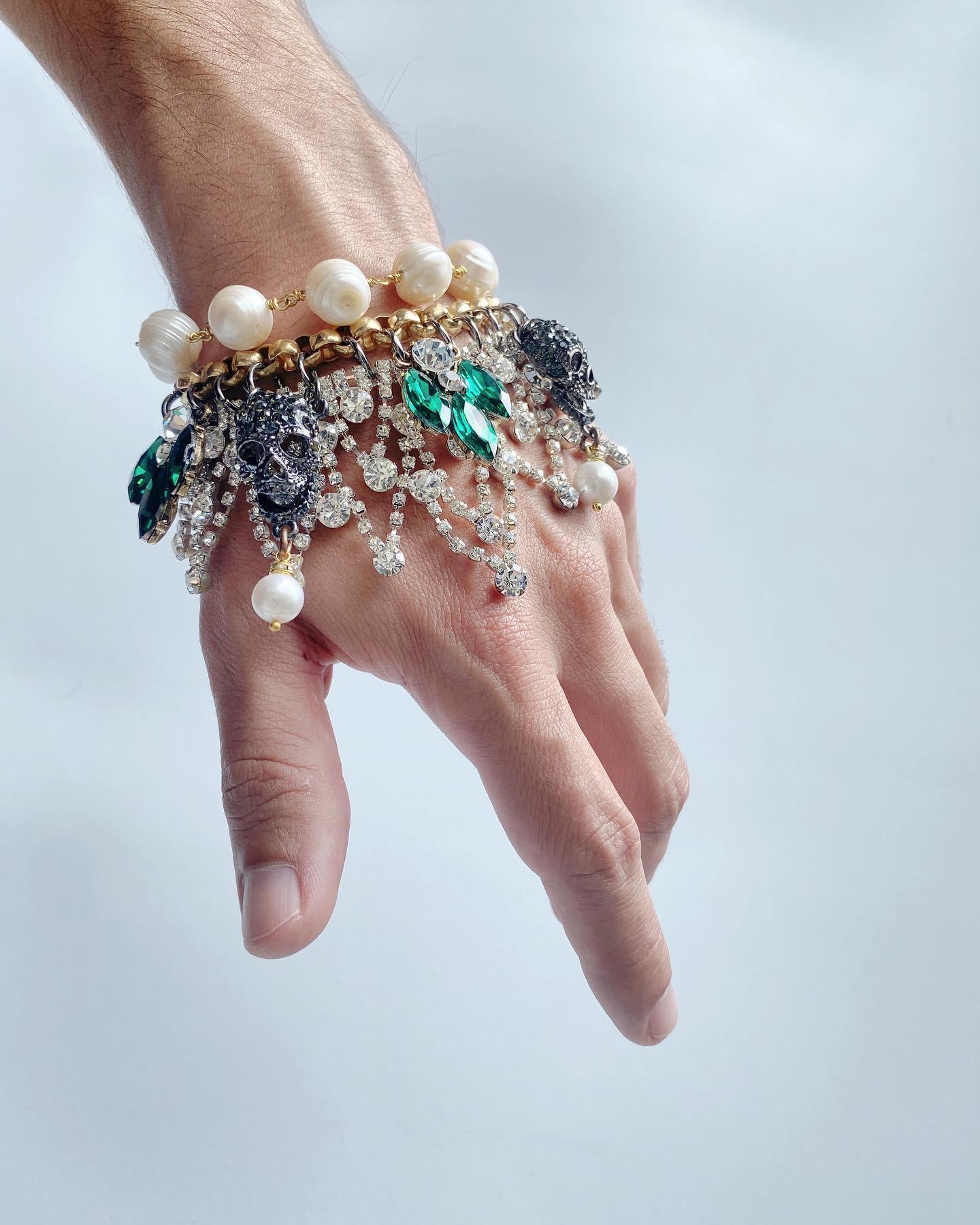 This bold and eye catching bracelet features black rhodioum plated skulls wirh freshwater pearls, accented with clear and rich emerald green Swarovsky crystals. 