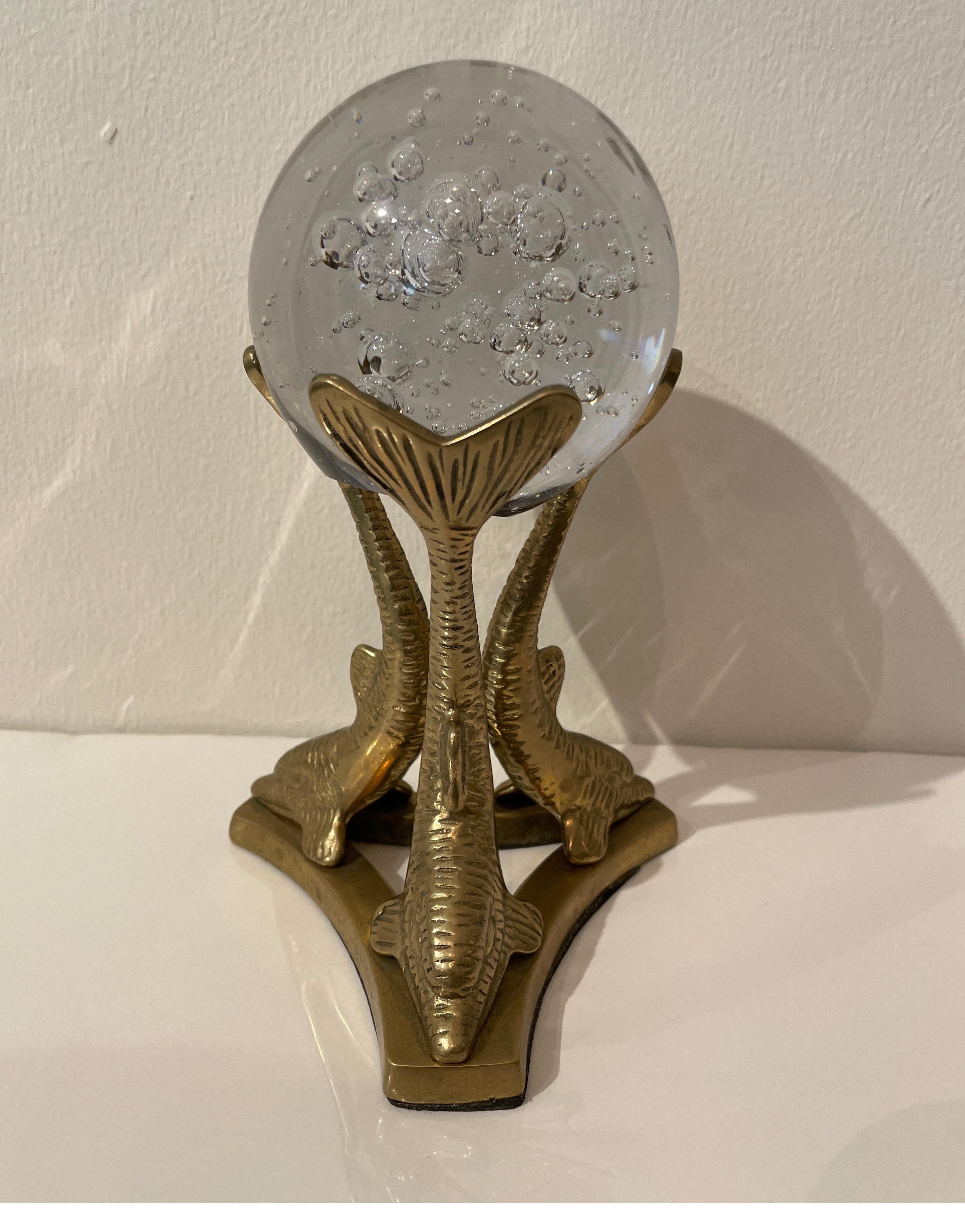 Crystal sphere with controlled bubbles supported by three brass dolphins.