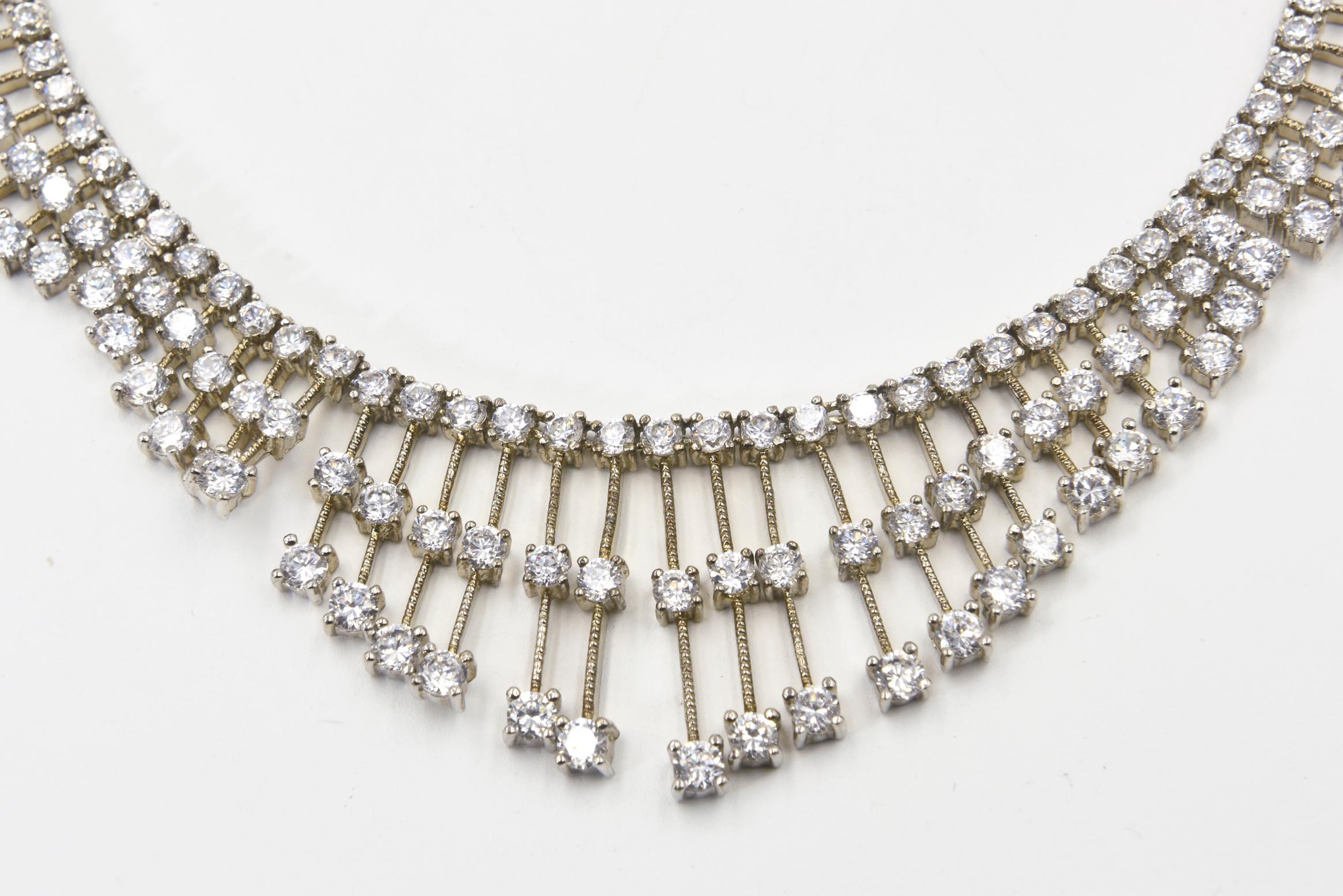 Red carpet style tassel bib necklace made up of various length lines that each have three prong set clear crystals.   The bars have a texture design that makes it look like a screw. The up-and-down pattern makes it look like waves going around the