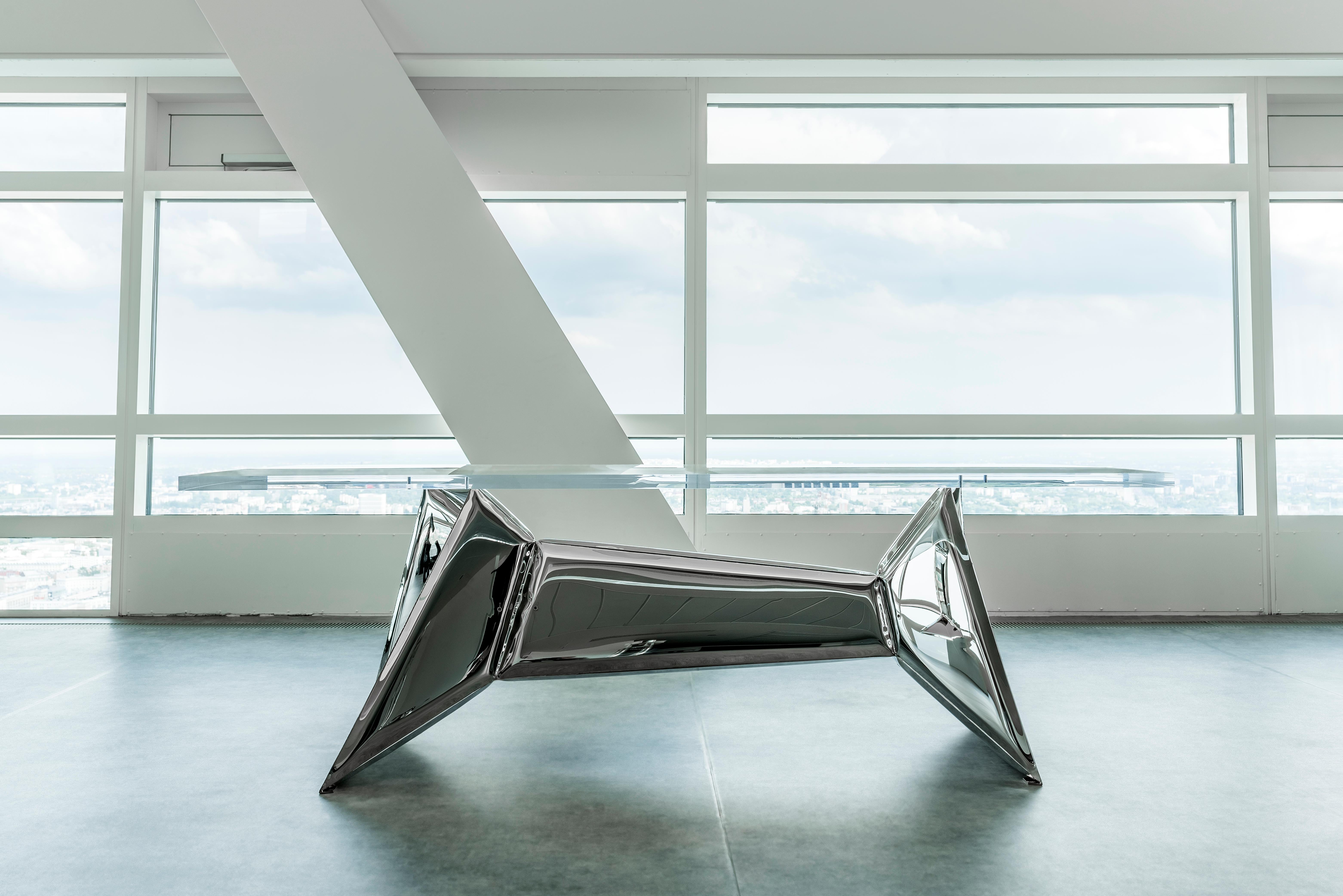 The Crystals table in stainless steel, Zieta
Dimensions: L 220 x W 110 x H 73 cm
Material: stainless steel and acrylic top.

Crystals is a series of mirrored objects combining geometric shapes with smooth, soft transitions of inflatable metal forms.