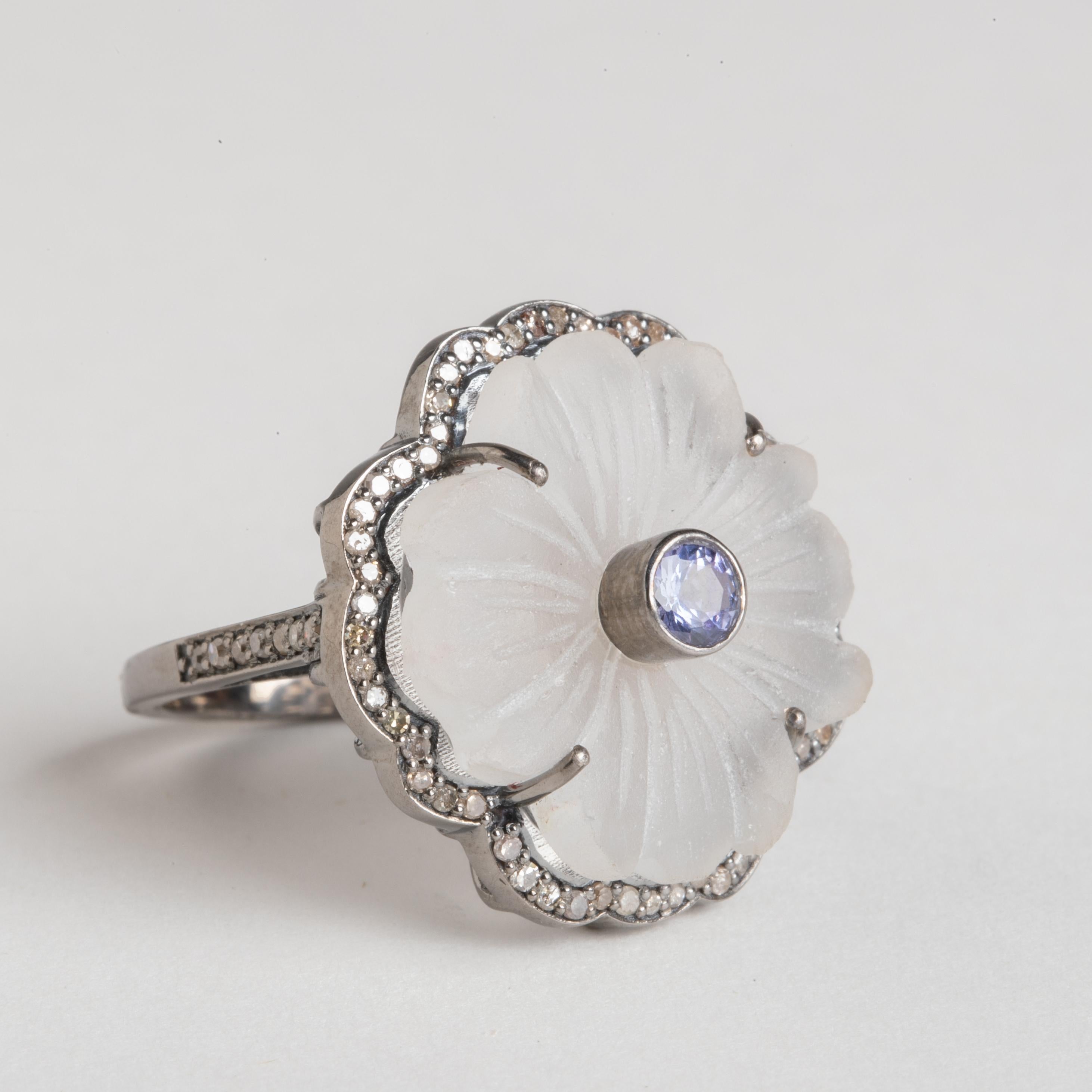 A carved floral crystal with a faceted tanzanite center stone.  Bordered with round, brilliant cut diamonds in a pave` setting.  All set in an oxidized sterling silver.  Diamonds along the side of the band as well.  Weight of crystal and tanzanite