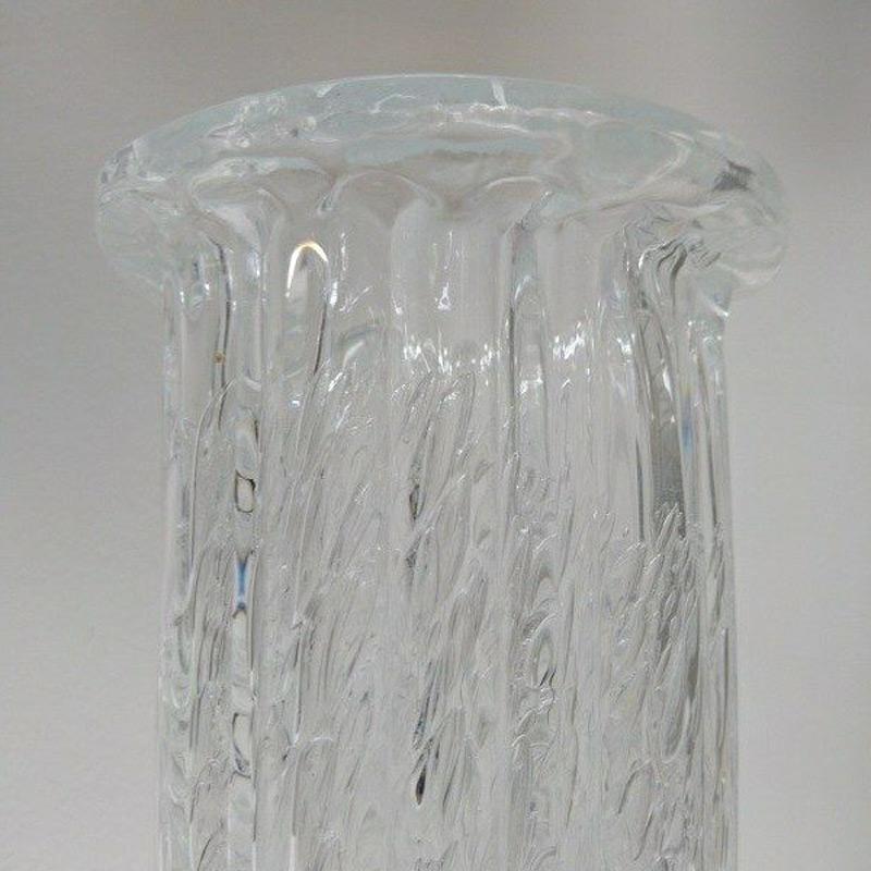 Beautiful relieffed crystal glass vase in Scandinavian art glass by Willy Johansson for Hadeland Glasverk, Norway, 1960s.
This oval shaped vase has thick walls with the icy look of vertically ribbed clear glass with many bubbles trapped within. Top
