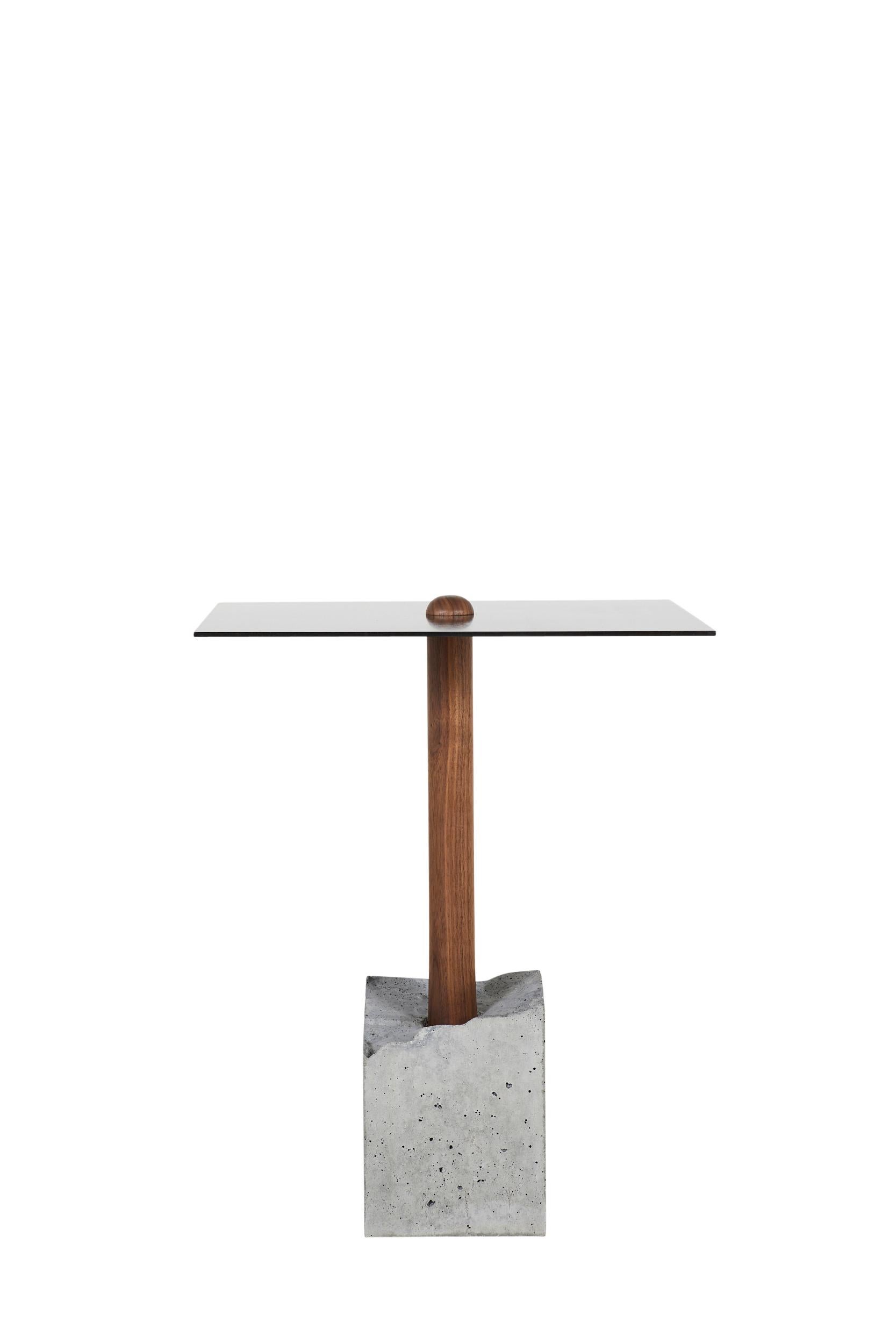 This simple and elegant design is composed of a hand-turned upright piece of wood that is cast into a concrete base. Shown in walnut, the concrete base is a rough 