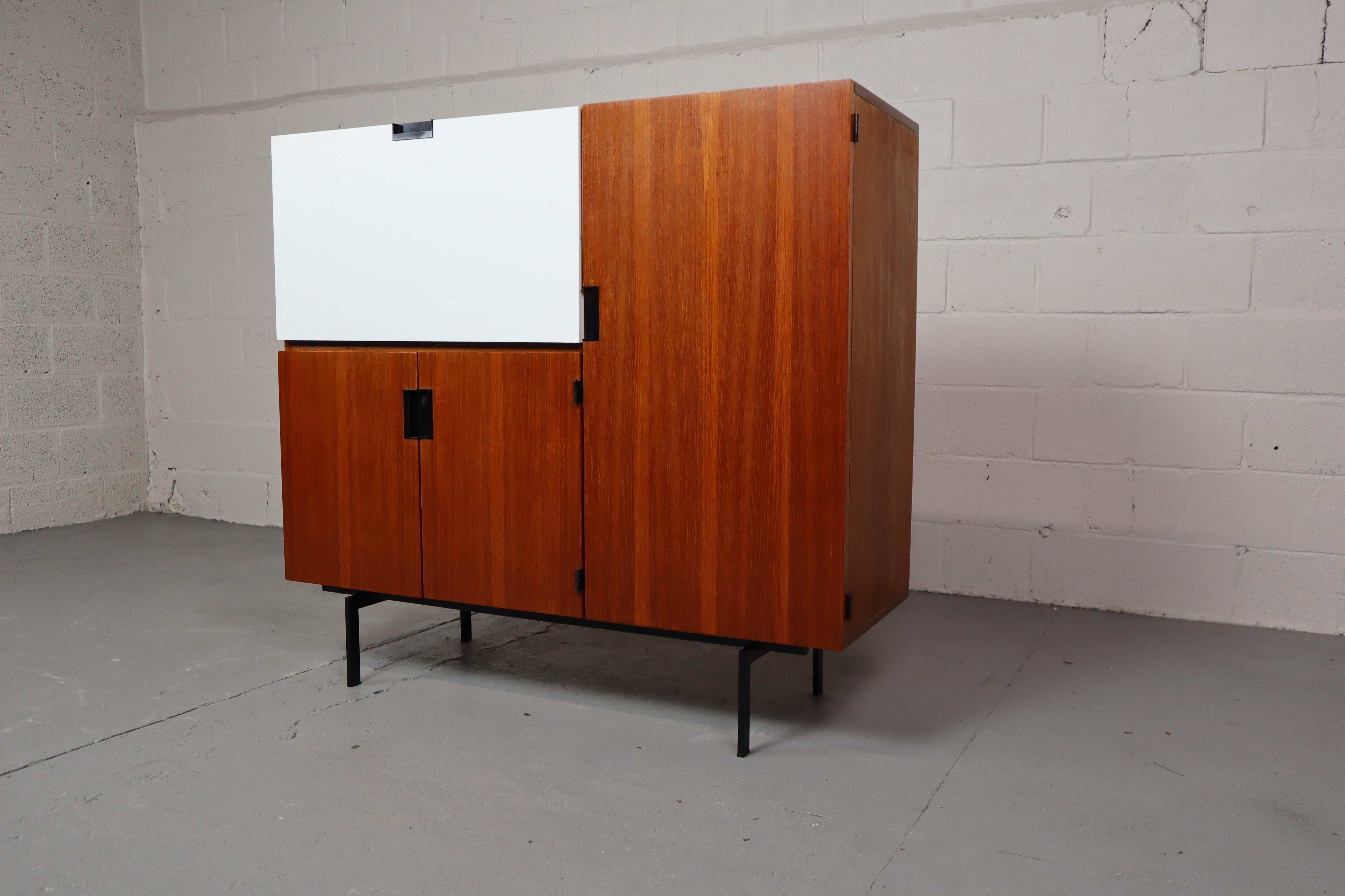 Model CU06 teak cabinet designed by Cees Braakman for Pastoe in 1958.
This model is part of the Japanese series and is a real Dutch design classic.
The CU06 model has a white drop down door on the left with a shelf, 2 folding doors underneath with a