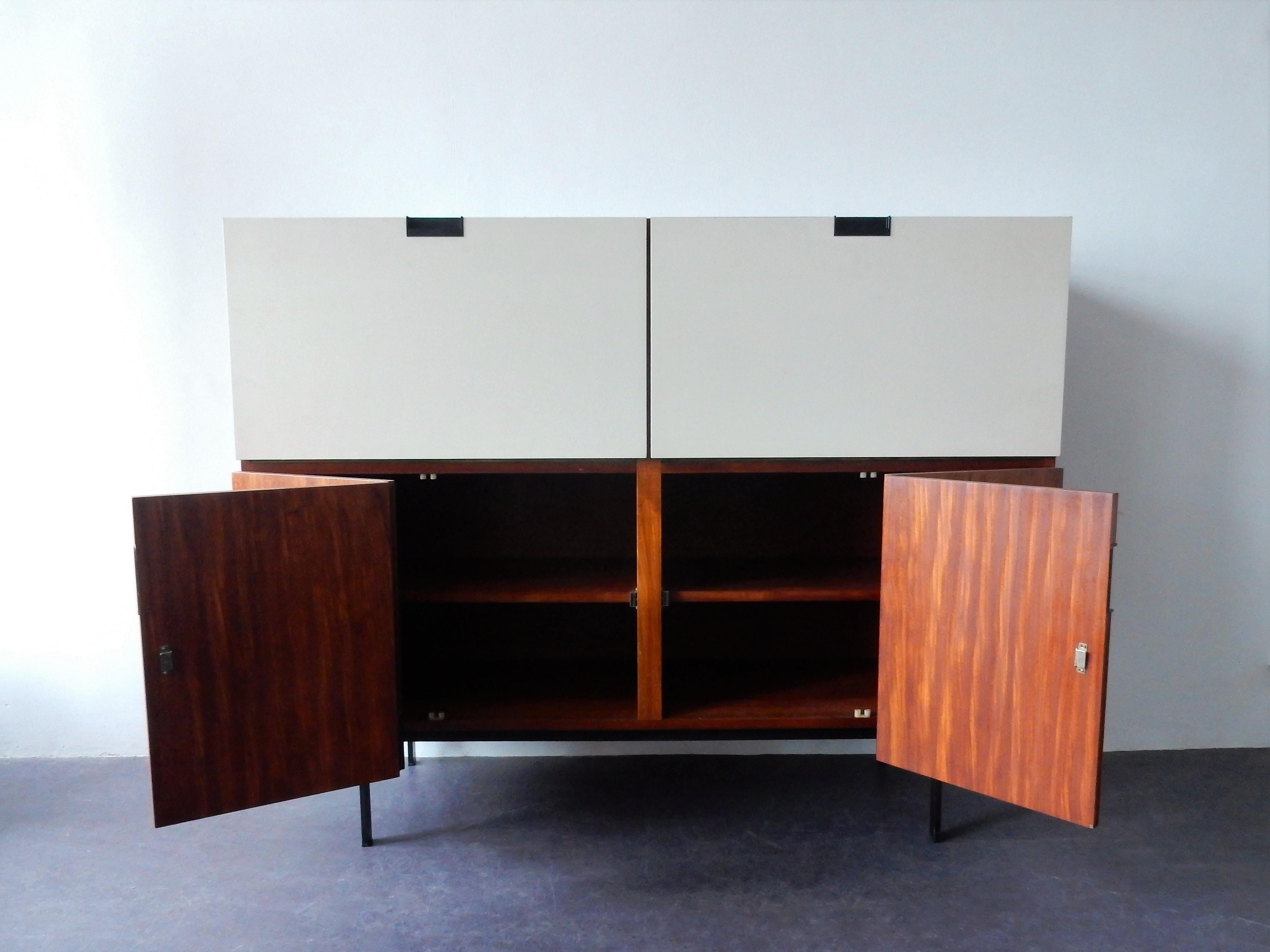 This very nice and highly collectable highboard, from the Japanese series, was designed by Cees Braakman for Pastoe in 1958. The cabinet is made from teak veneer combined with two white lacquered dropdown doors, iconic black integrated handles and a