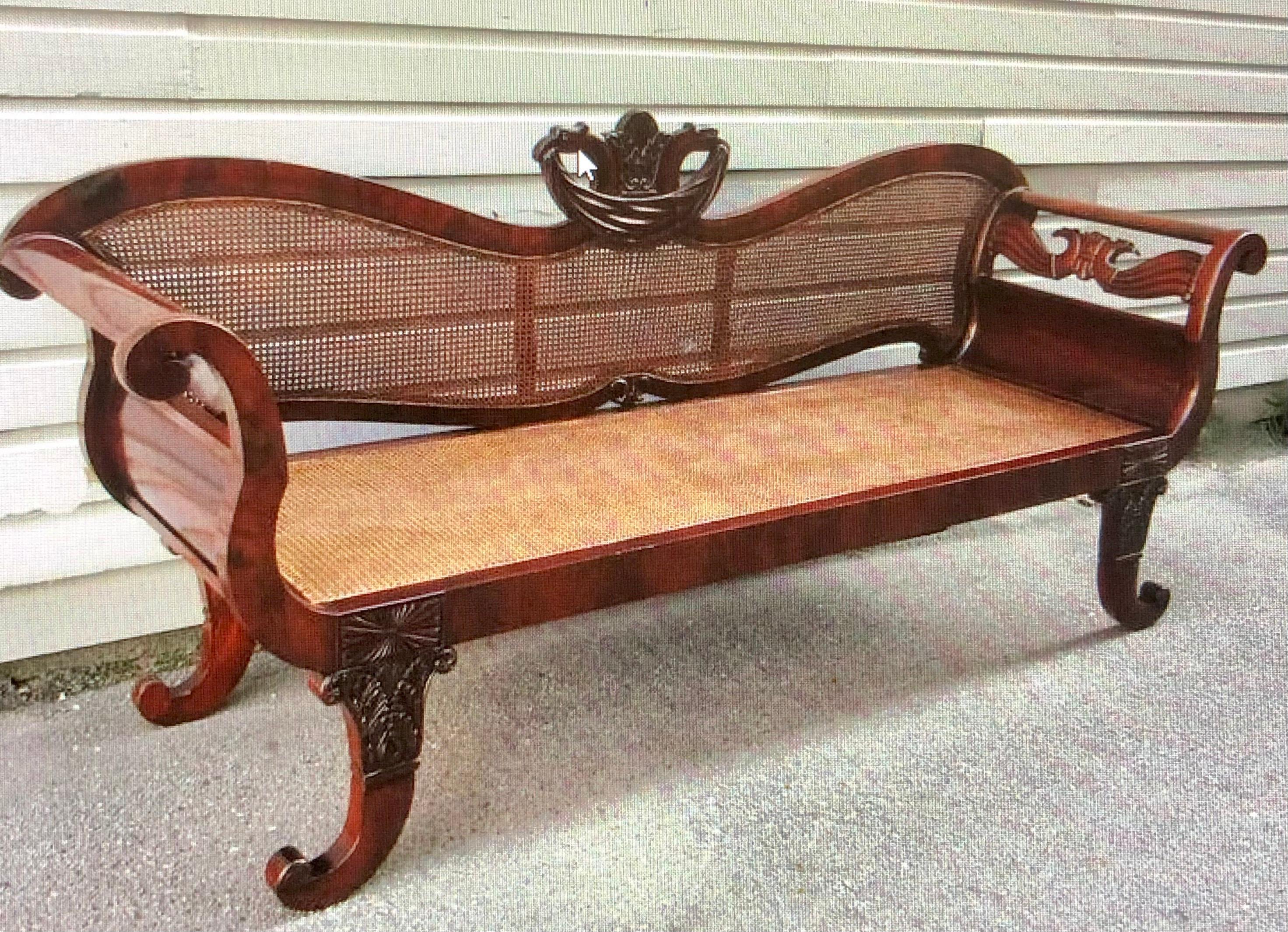 Notable Cuban Empire Mahogany caned sofa, circa 1820, featuring Flame Mahogany veneers and opposing Eagle carvings. The center crest of this Caribbean Settee has a Pineapple motif flanked by Regal Bird Heads clasping drapery from their beaks rest on