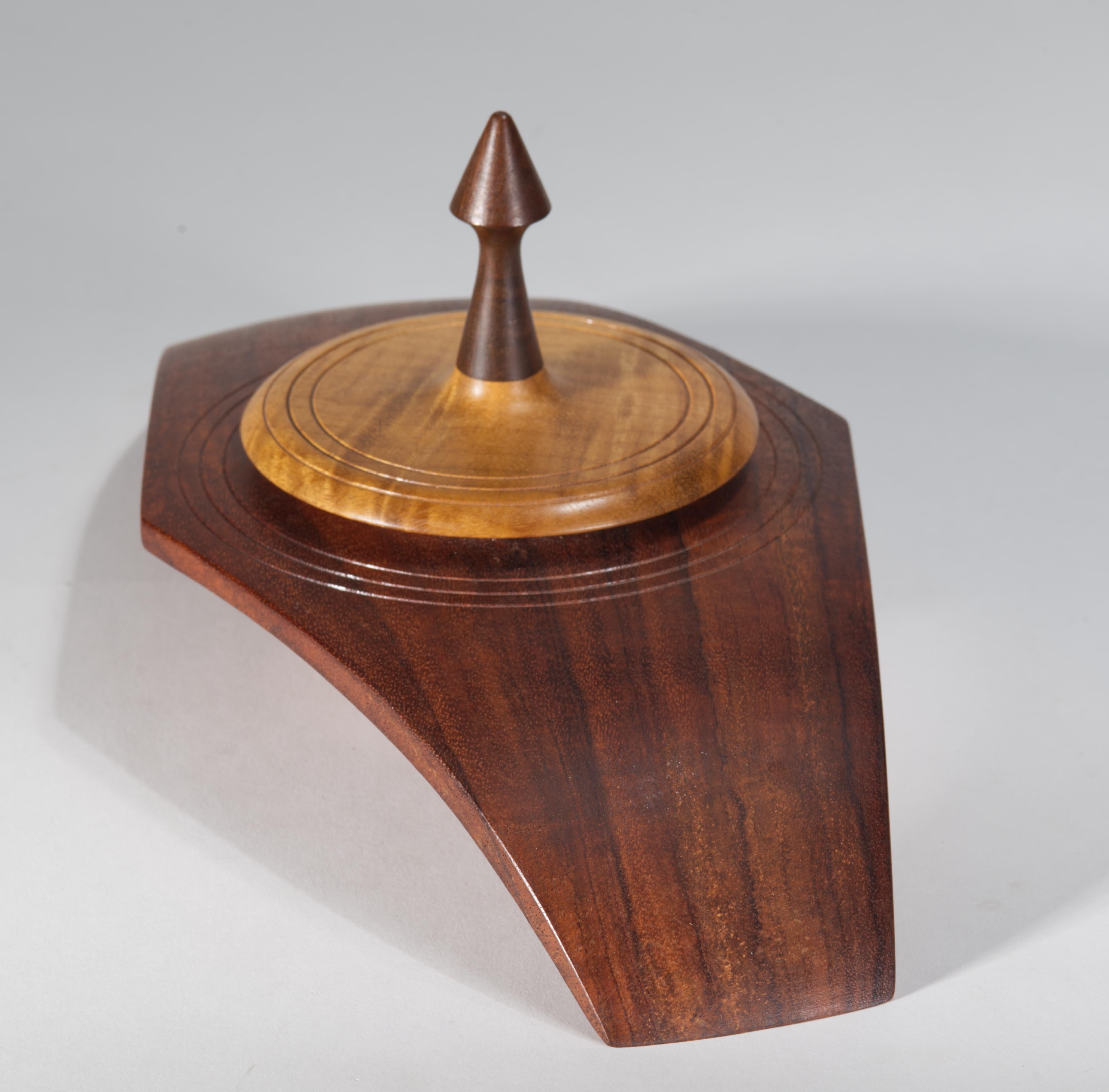 La grande scatola decorativa vintage con coperchio rotondo presenta una forma scultorea realizzata a mano, intagliata in legno di Koa, Murtle e Redwood. La texture fine del legno è enfatizzata dal contrasto grafico tra le diverse specie di legno e