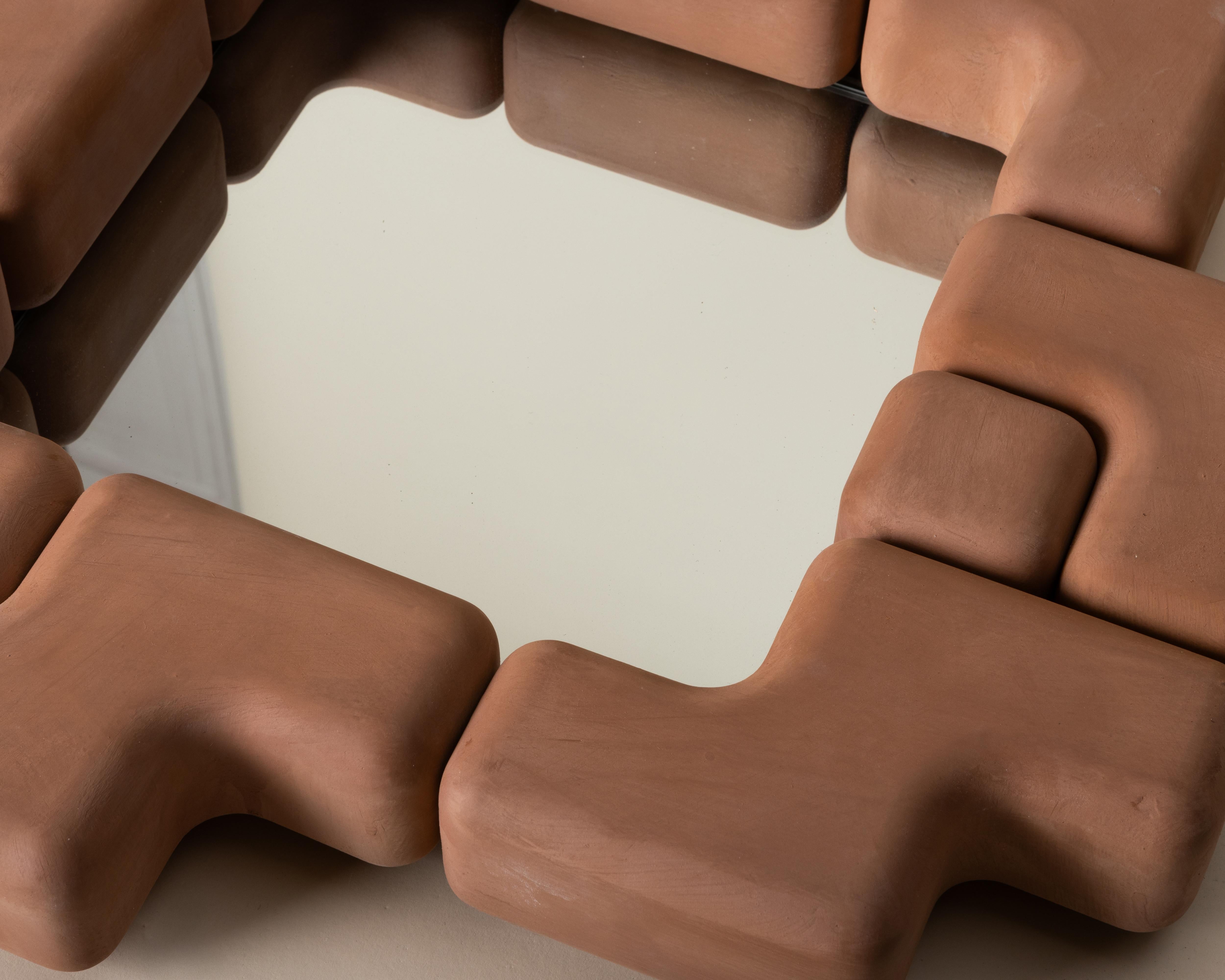 Il Cube Fit Mirror è uno specchio da parete scultoreo realizzato con forme di ceramica modulari a incastro. Fusa a mano negli Stati Uniti, l'audace cornice circonda uno specchio di vetro quadrato, creando un ritmo giocoso di geometrie ripetute. Ogni
