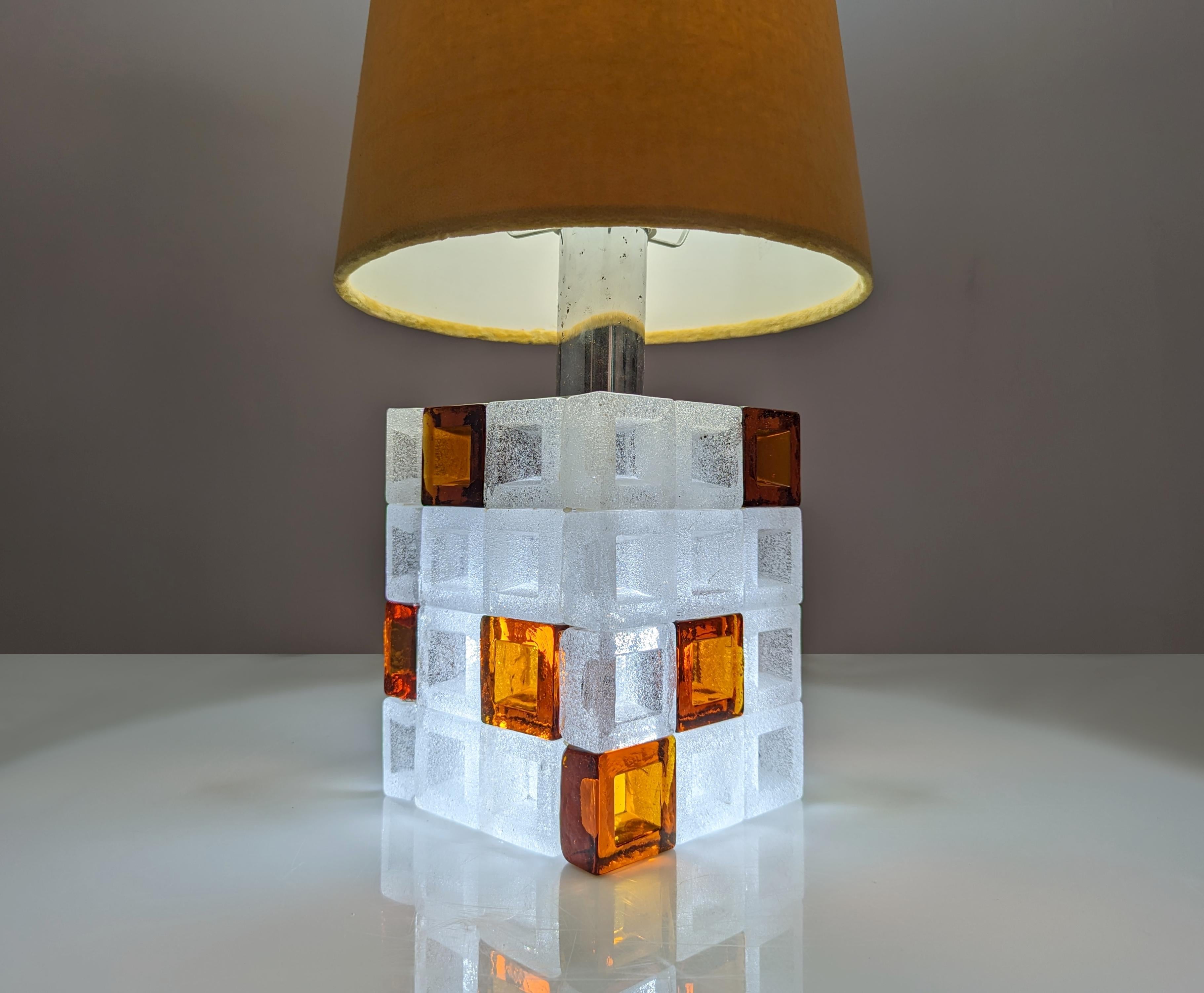 Immerse yourself in the golden age of Italian design with this exquisite lamp by Albano Poli, a timeless masterpiece that blends the craftsmanship of Murano glass with the creative vision of the 1960s. Fused glass cubes in ice white and amber tones