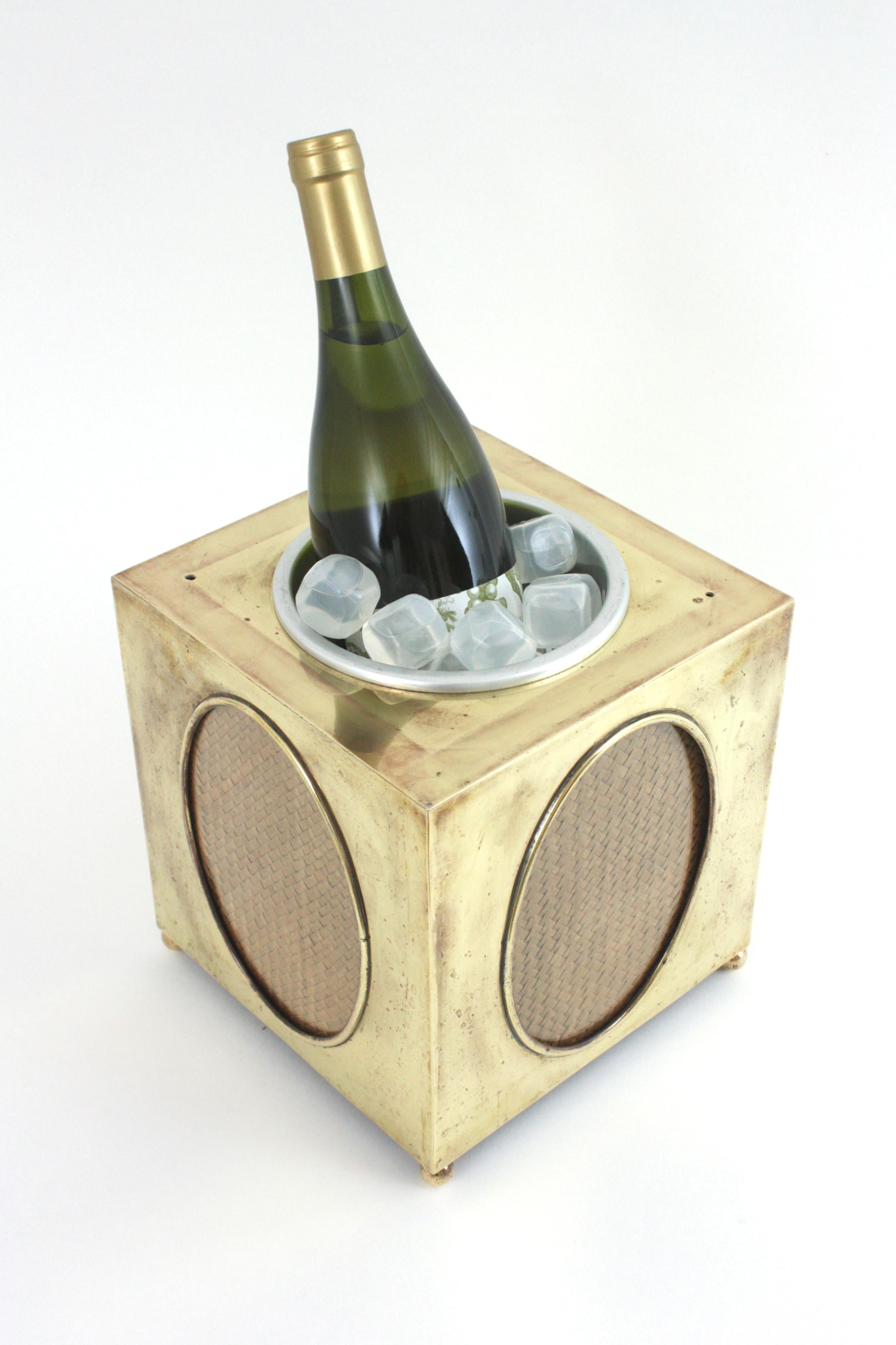 Cubitera italiana de latón Hollywood Regency con paneles ovalados de mimbre y cristal, 1940-1950.
Elegante enfriador de vino en forma de cubo de latón con paneles de cristal ovalados en los cuatro lados decorados con mimbre tejido. Coronado por una