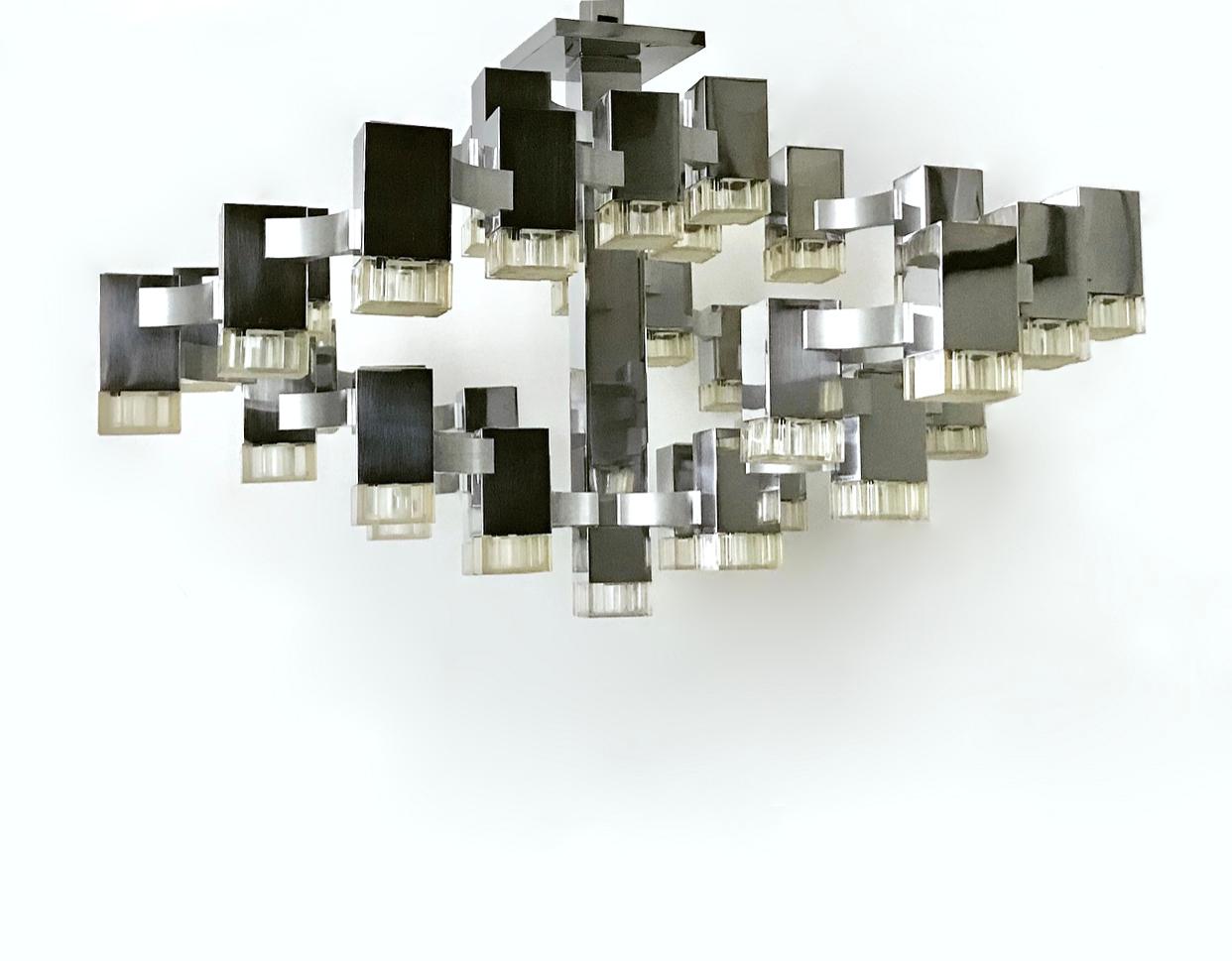Cubic chandelier by Gaetano Sciolari in polished stainless steel with brushed aluminum connective supports and molded plastic diffusers. Each light has one US candelabra socket and the fixture is shown illuminated with 15W bulbs. Original canopy