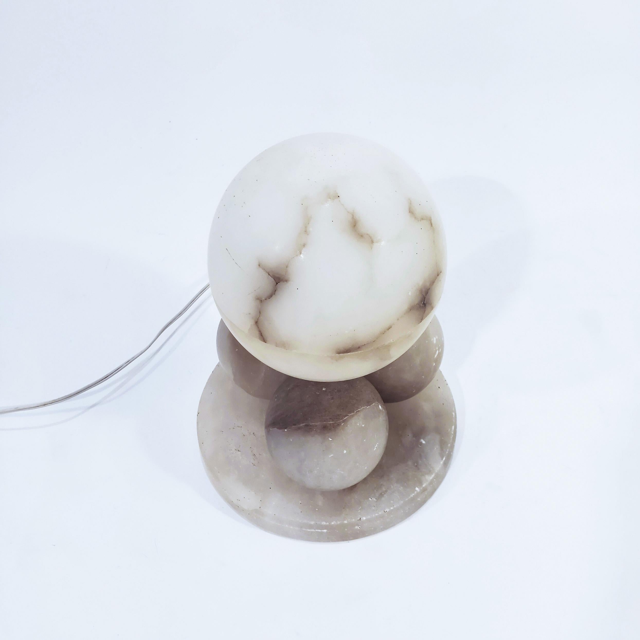 Art Deco and Cubist style table lamp made of turnet alabaster, Spain, 1950s. Composed by 3 solid alabaster spheres on a solid circular base of the same material, on which rests another larger sphere hand-carved inside that houses the lamp holder.