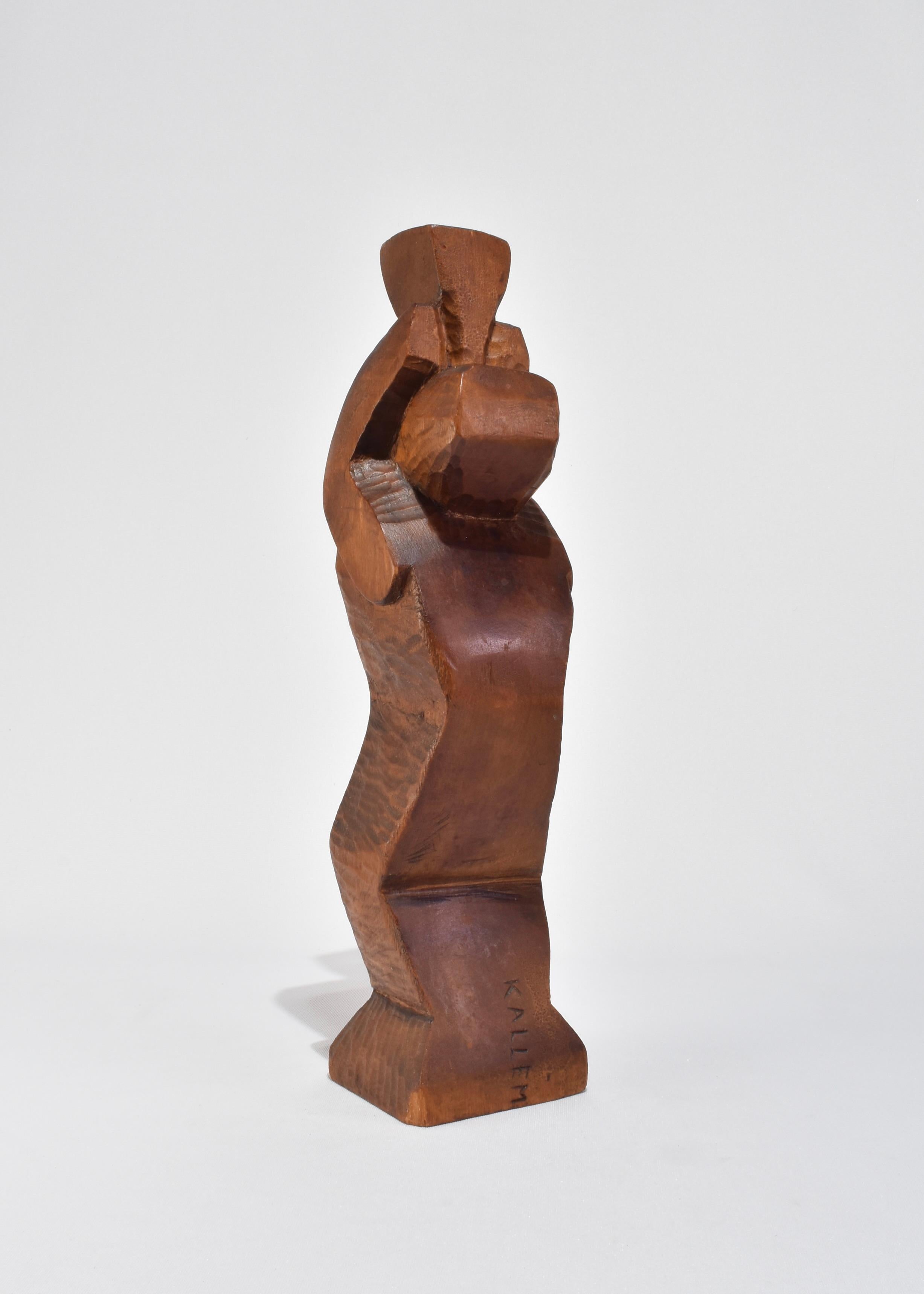 Escultura abstracta de madera tallada a mano con forma escalonada y angulosa y planos facetados. La silueta evoca influencias cubistas con su geometría en bloque y sus bordes suavizados. Firmado Kallem en la base.