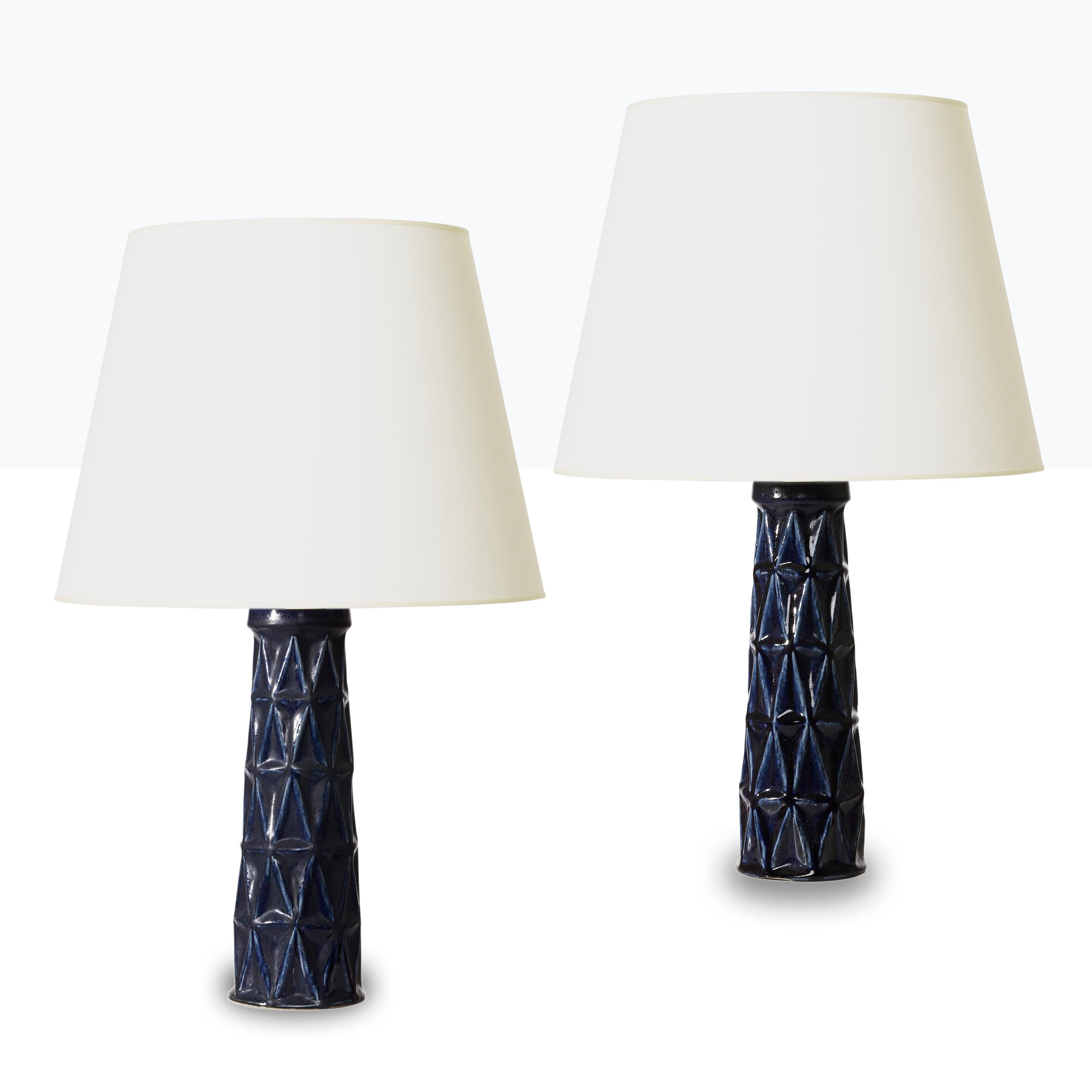 Near pair of table lamps with cubist relief designed by Leon Henri Galleto (1931-2009) for Saxbo. in stoneware with deep blue glaze, Denmark, mid-20th century, impressed with “Saxbo” stamp. Alike in form and tone of glazing, one has a matte finish,