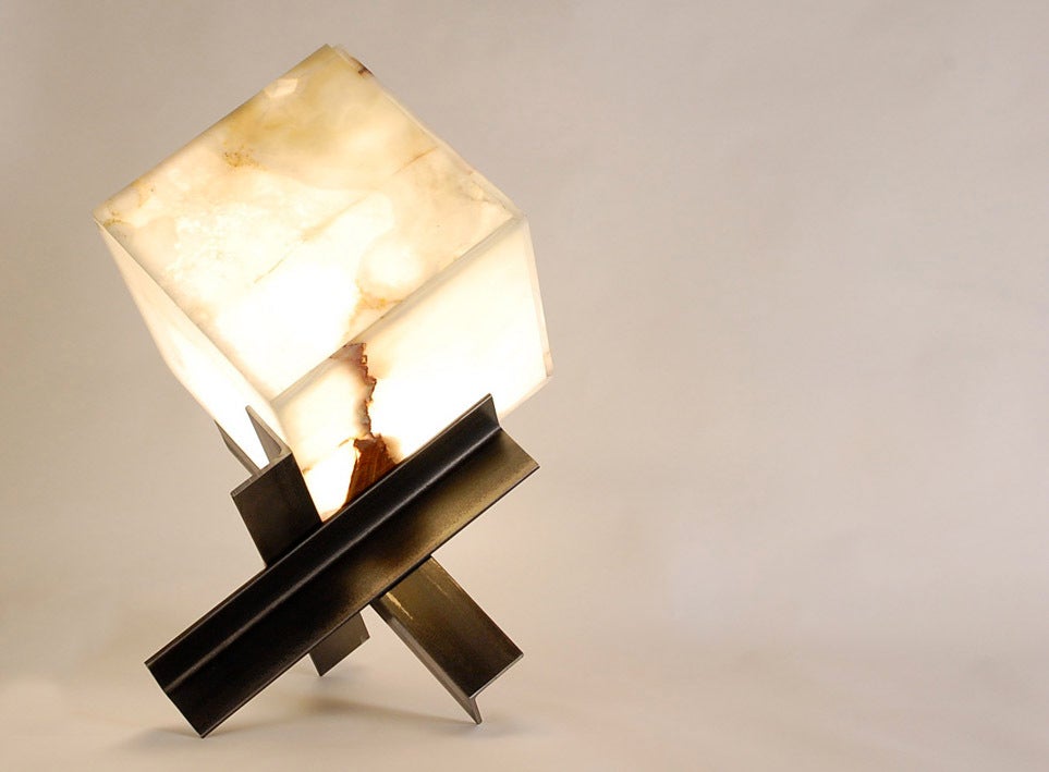 The sculptural 'Cubyx' lamp is made of a jointed translucent onyx panel cube placed on a tripod base. The bulb is changed by lifting the top portion (3 jointed panels) of the cube.