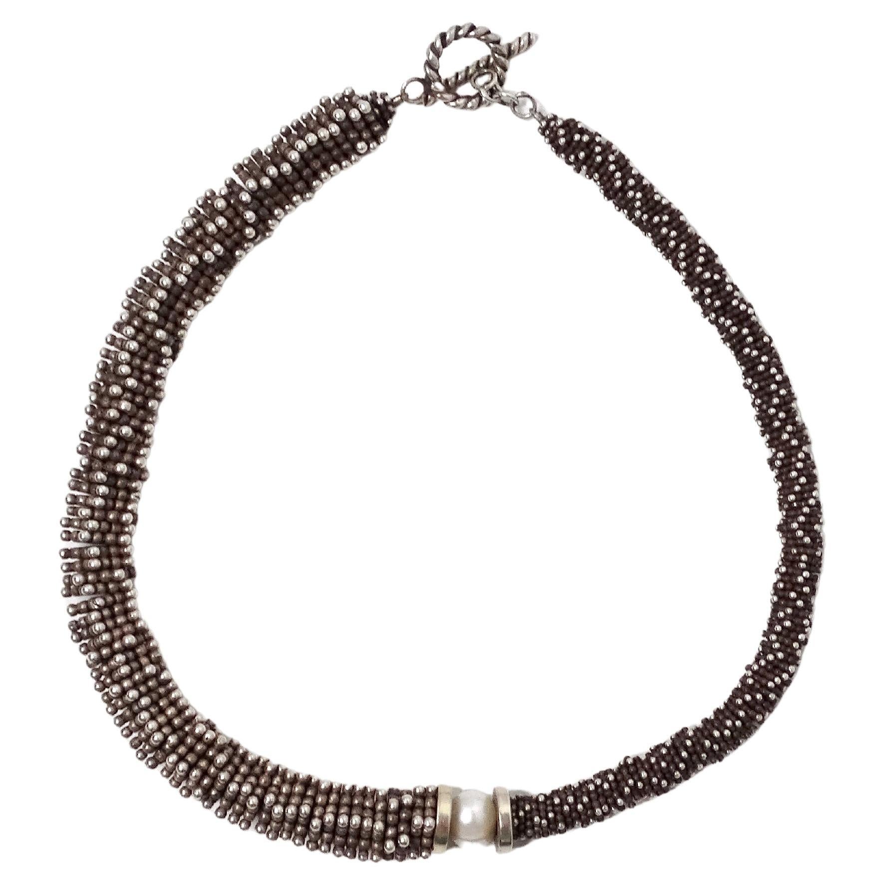 La collana Cucinelli-Like Asymmetrical Silver-Tone Spiral Beaded Necklace è un pezzo straordinario che incarna l'eleganza e il design contemporaneo. Realizzata con un effetto argento antico, questa collana è caratterizzata da un'esclusiva formazione