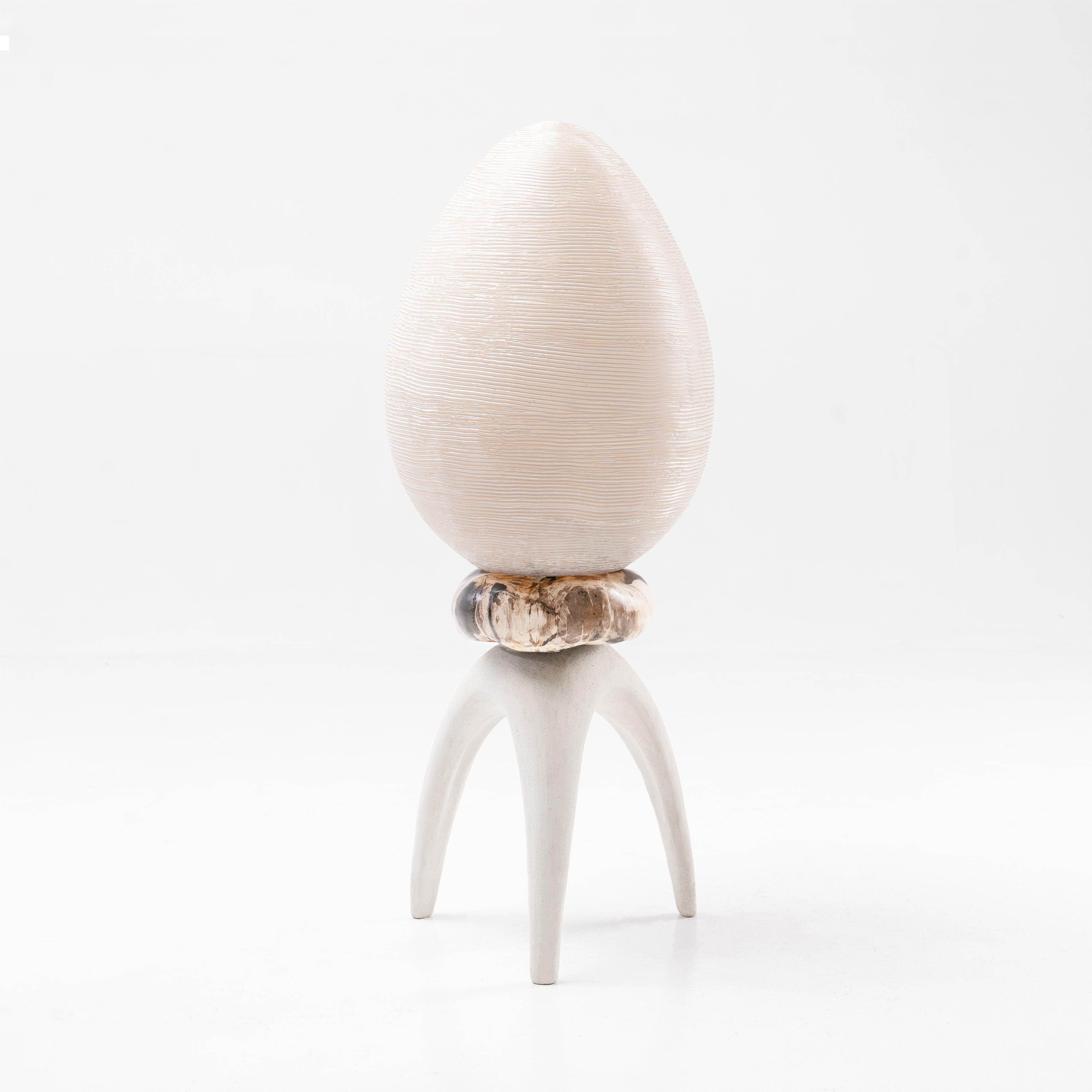 Une lampe sculpturale au design biophilique. Cette lampe en forme d'œuf, sculptée à la main, est posée sur une pièce en bois pétrifié de forme organique, sur une base en forme de pierre calcaire. 

Dimensions : L40 x P40 x H110 cm // 15.8 x 15.8 x