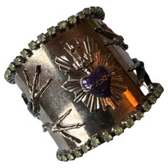 Brazalete Corazón Sagrado, esmalte morado y azul, estrás verde