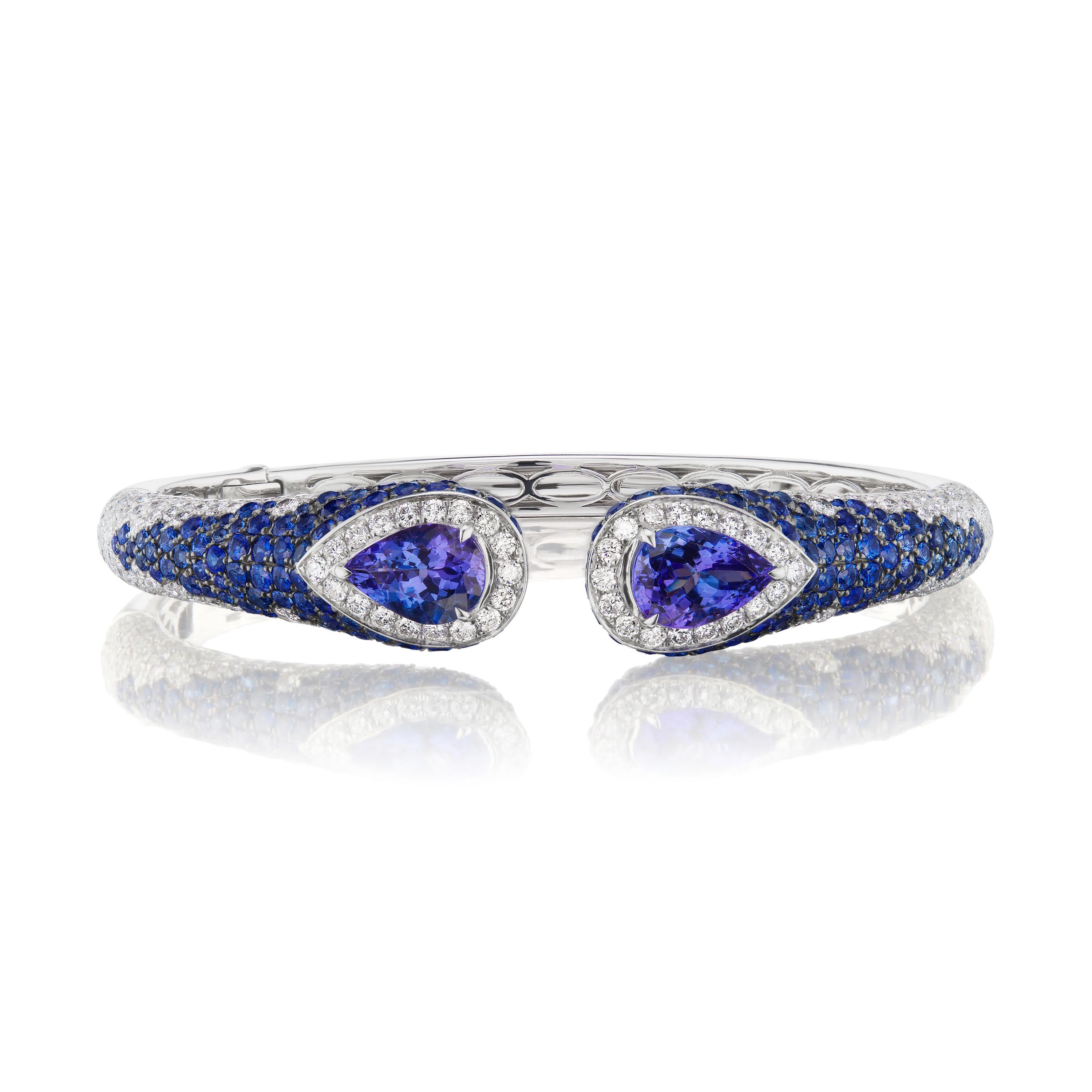 The dazzling blue artistry is done around the pear 4.36 carat blue tanzanite prong set in a dazzling halo of white diamonds. The shoulders of the bangle are further accentuated by the spray of 4.38 Ct. t.w. blue sapphire and white diamonds around