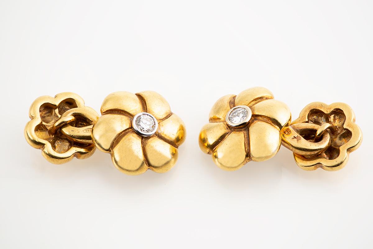 A heavy quality pair of 1960’s vintage double sided cufflinks in 18 karat gold. Shaped in the design of a six petalled flower head in two sizes. The larger face has a brilliant cut diamond centre and the smaller face, a white gold centre. The figure