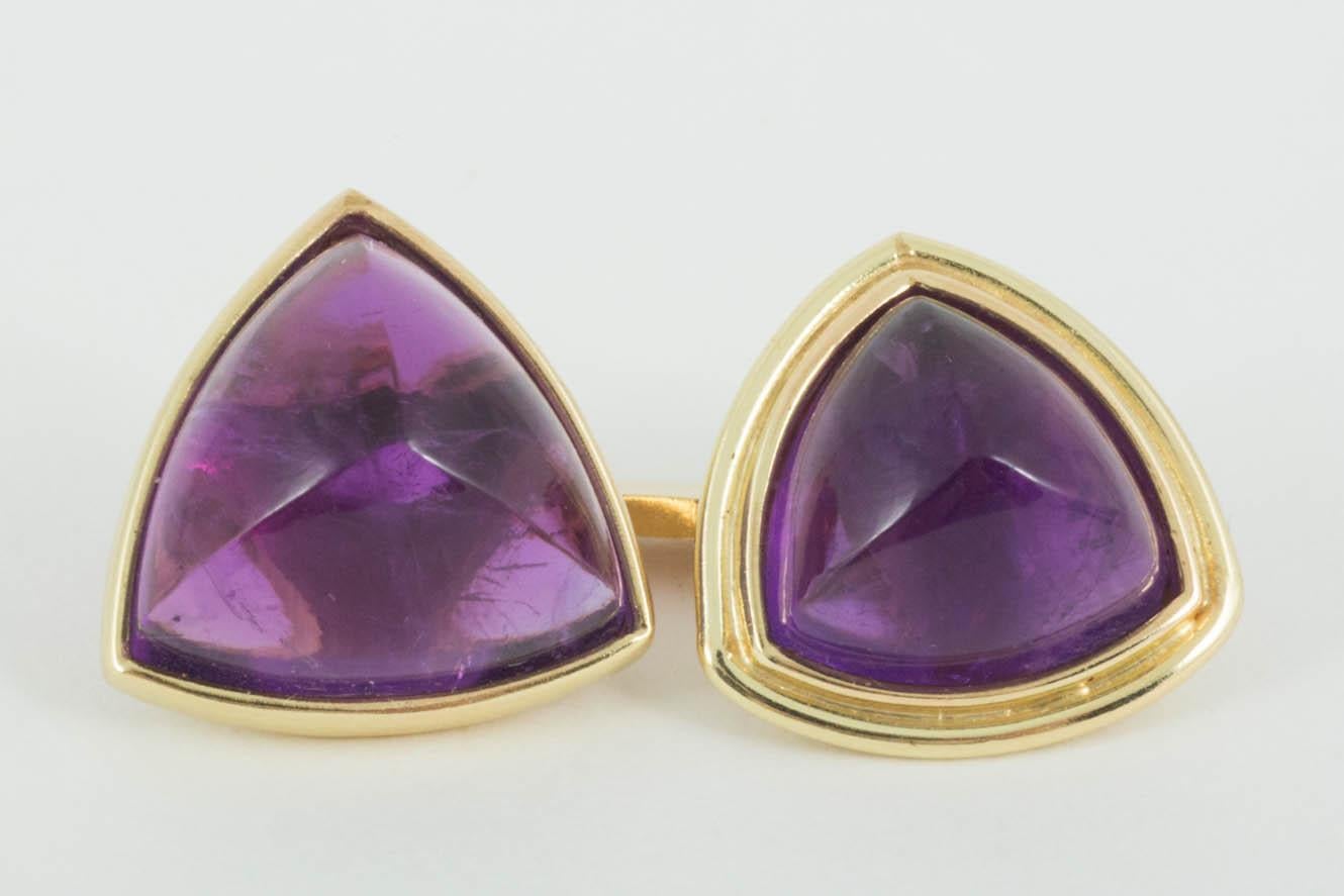 An unusual pair of 1920's antique double sided cufflinks in 18 karat yellow gold with triangular mounted amethysts. The cabochon shaped amethysts are of particular fine colour with 2 styles of setting. One half of the link has a wider gold border