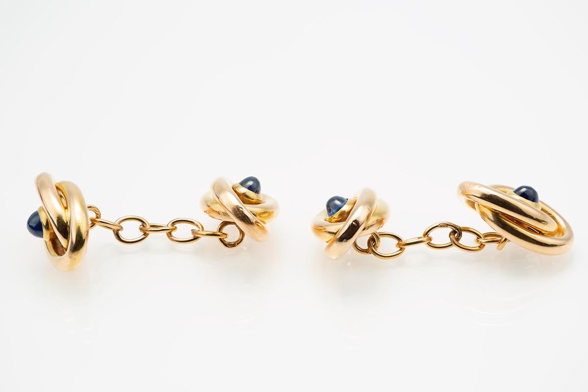 A finely made pair of double sided, 18 karat , yellow gold cufflinks of entwined loops, with a central, cabochon shaped Ceylon sapphire of fine colour, chain link connections. French marked with the Eagles head, measuring 10 mm in width, and 15 mm