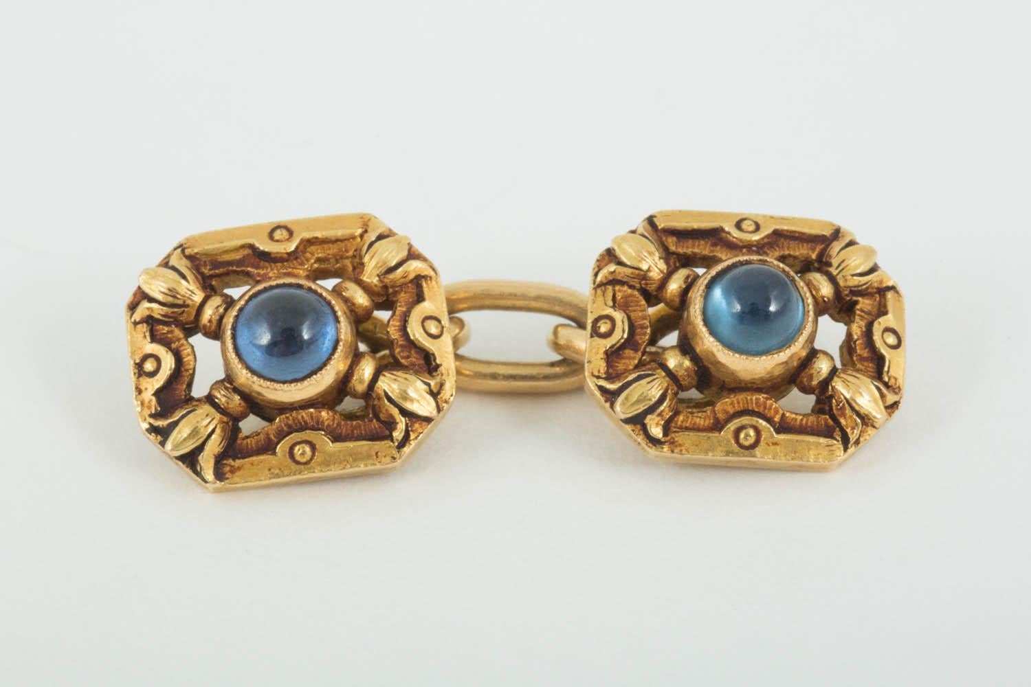 A heavy pair of 18 karat yellow gold cufflinks with floral carving, in an openwork form,each set with a cabochon cut sapphire centre,the goldwork of good colour.French marked withe the Eagles head.Circa 1900