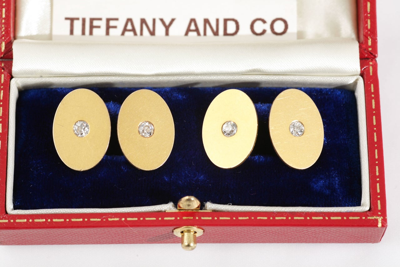 A pair of Tiffany and Co. 18 karat yellow gold double sided cufflinks of oval form, with a fine and original patina, the centre set with an old cut brilliant diamond. Signed Tiffany & Co and stamped 18k for 18 karat gold.
Measures 13mm in width and