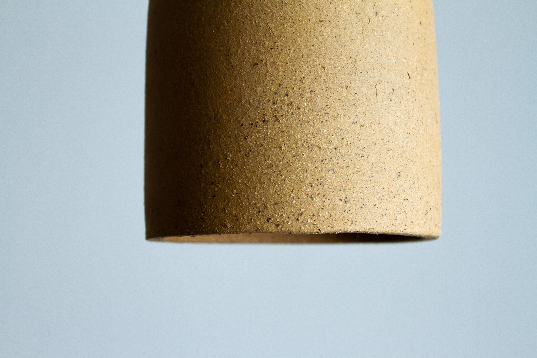 La lampada a sospensione Cuia fa parte della collezione Romaria, è stata sviluppata da Raísa Anderson, creativa del marchio, e prodotta all'interno di San Paolo - BR, a partire dall'argilla, dalle mani di Luis Airton, un ceramista partner con oltre
