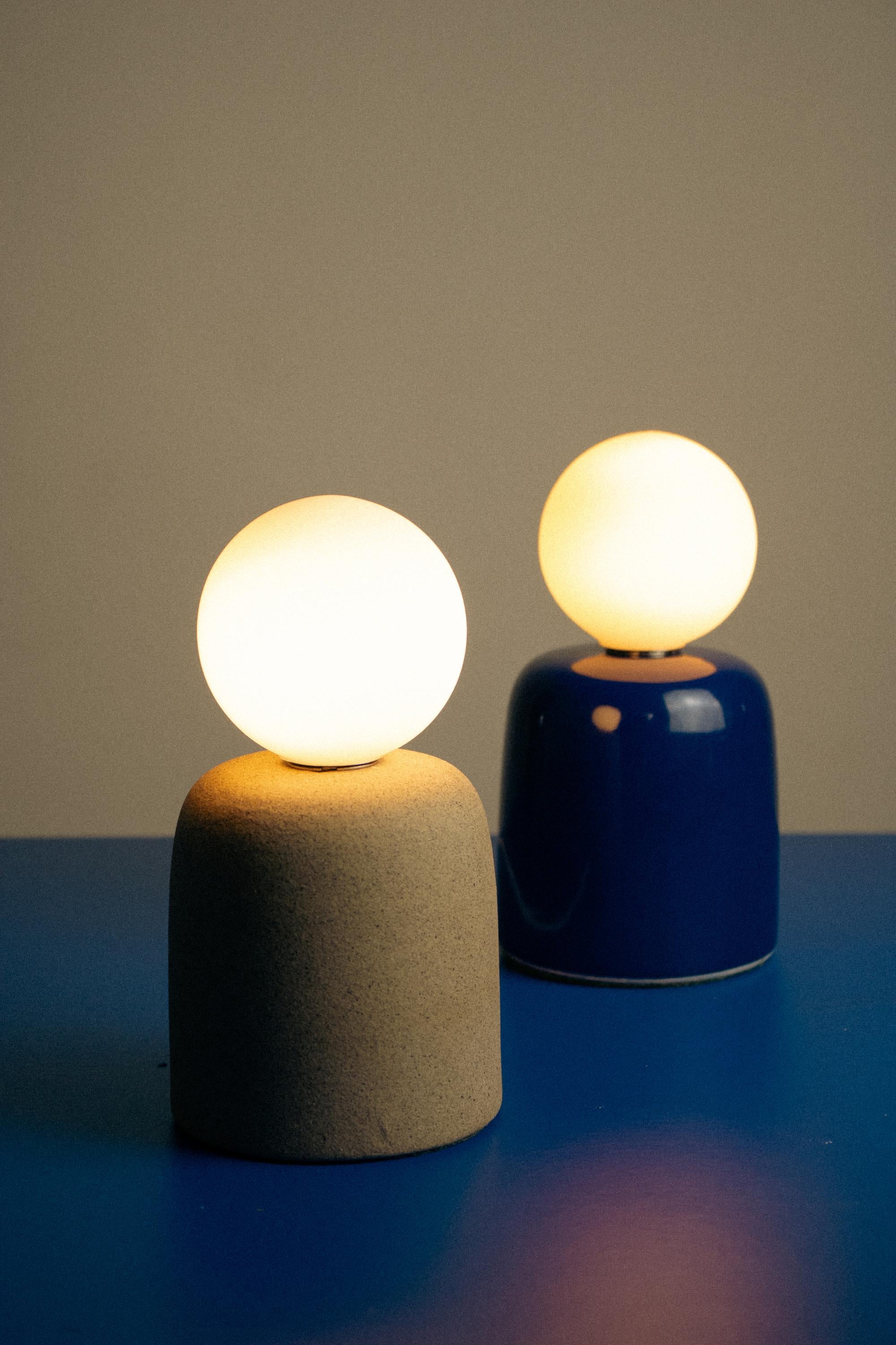 La lampe à poser Cuia fait partie de la collection Romaria, elle a été développée par Raísa Anderson, créatrice de la marque, et produite à l'intérieur de São Paulo, à partir d'argile, des mains de Luis Airton, céramiste partenaire avec plus de 30