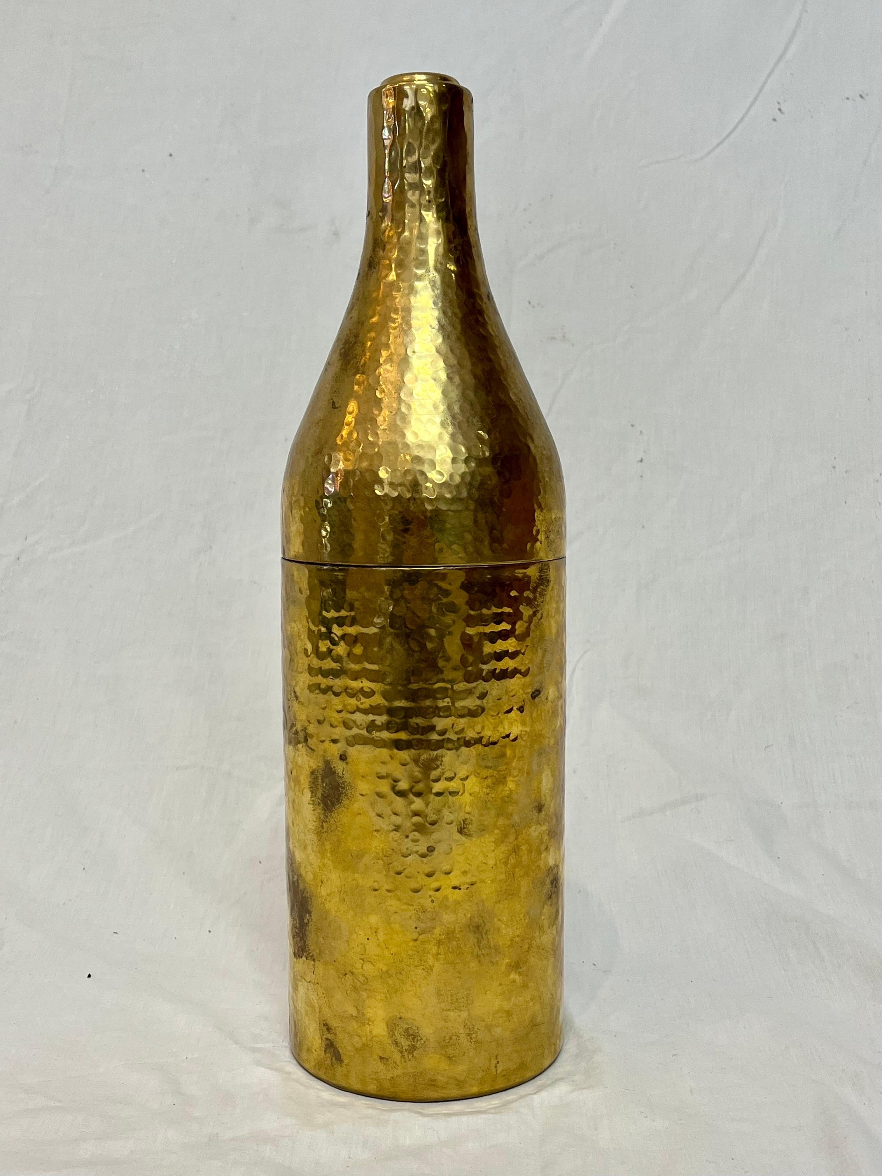 A festive and fun figural wine bottle holder by English brand Culinary Concepts. The mottled brass finish has a hand-hammered appearance lending to its appeal. The overall patina shows areas of wear and use. The top of the bottle is removable and