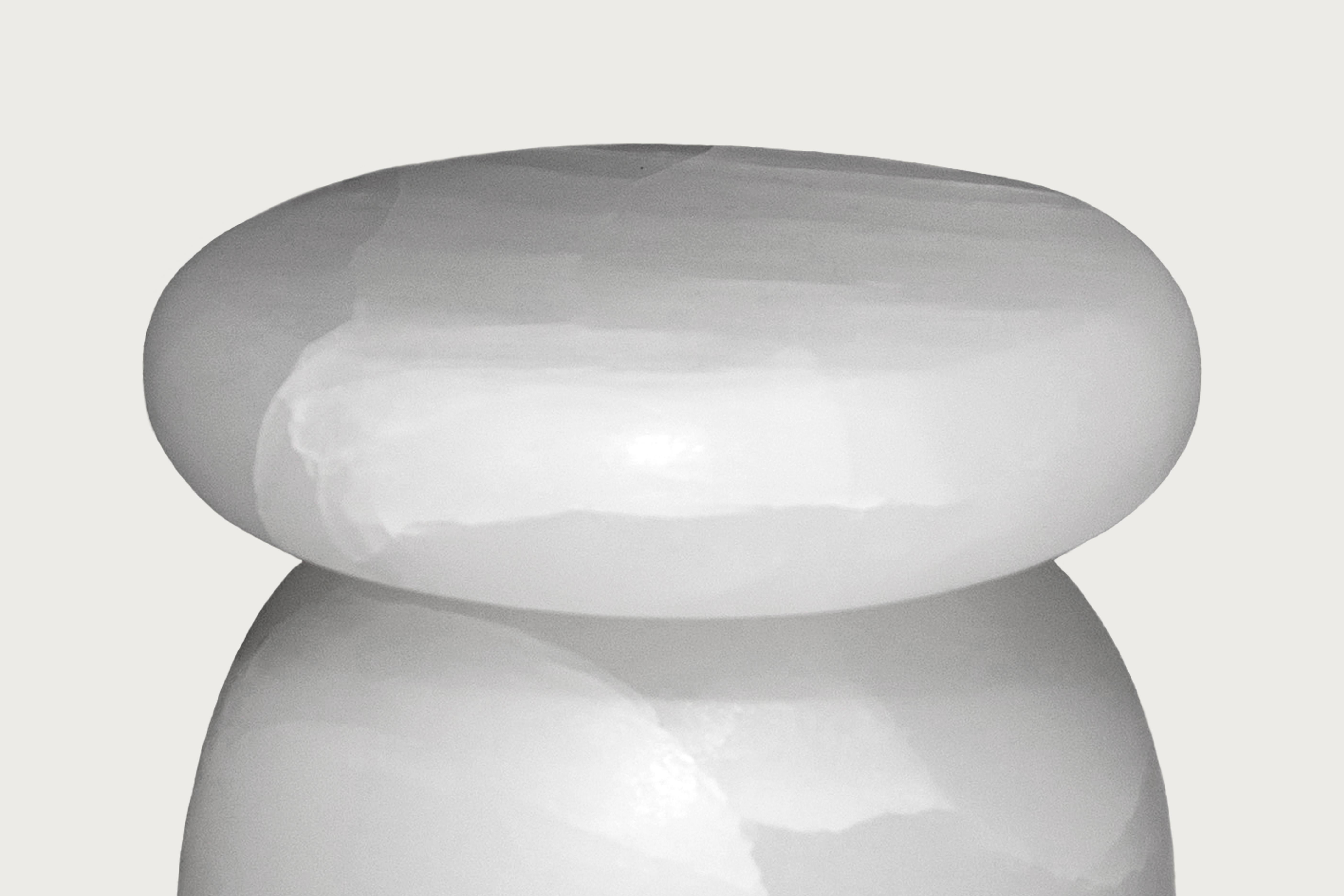 Cult stool / side table; a hand sculpted stone from an incredibly particular stone; Mexican Ice Onyx, remits to primal sculptural-architectural language while displaying materials in a modernist manner. The piece allows for the specificity of the