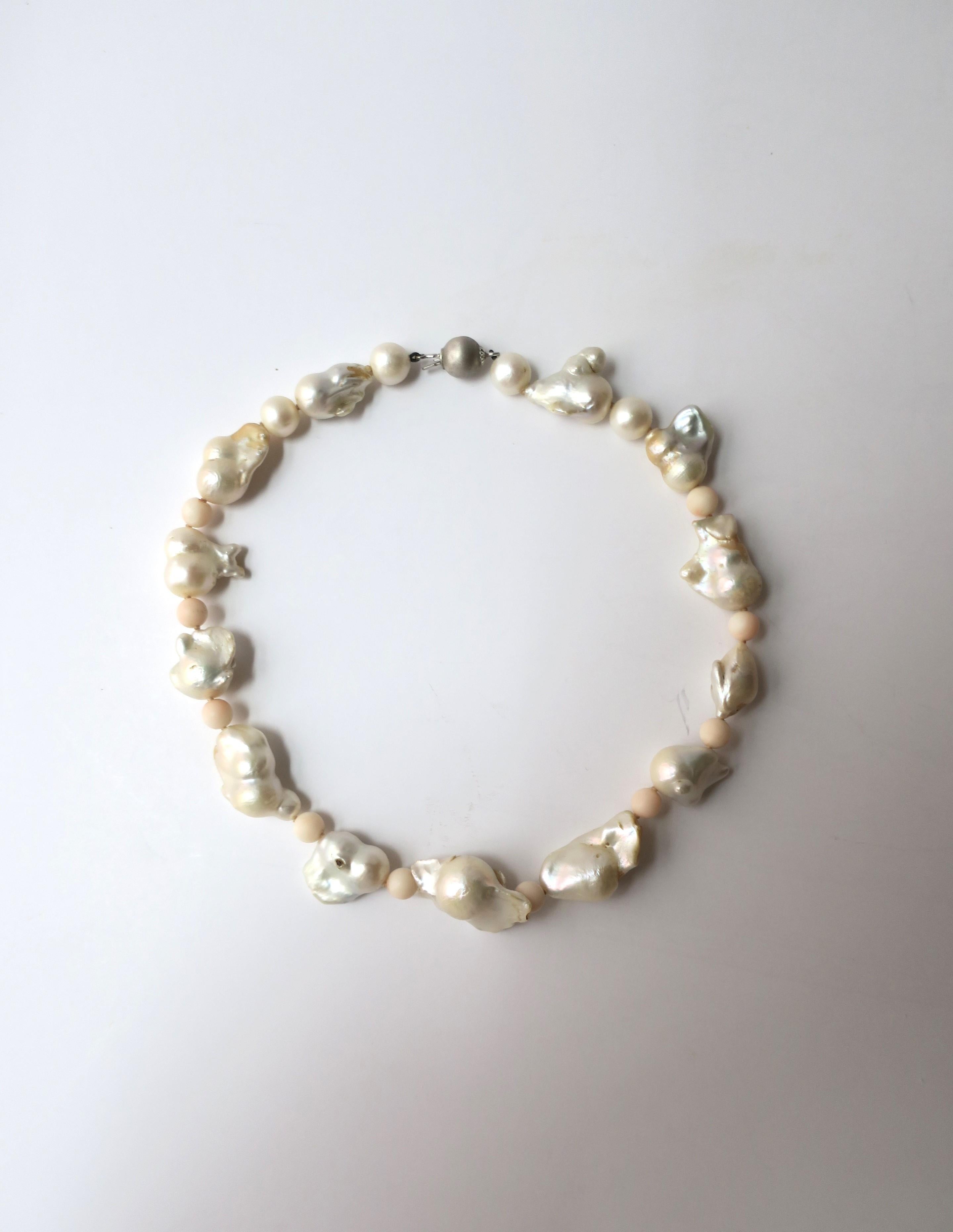 A very beautiful necklace of large baroque white freshwater pearls, light pink coral beads, cultured white pearls, and one 18-karat white gold bead/clasp (looks like a gray pearl.) Necklace is beautifully strung with knotting in-between each pearl