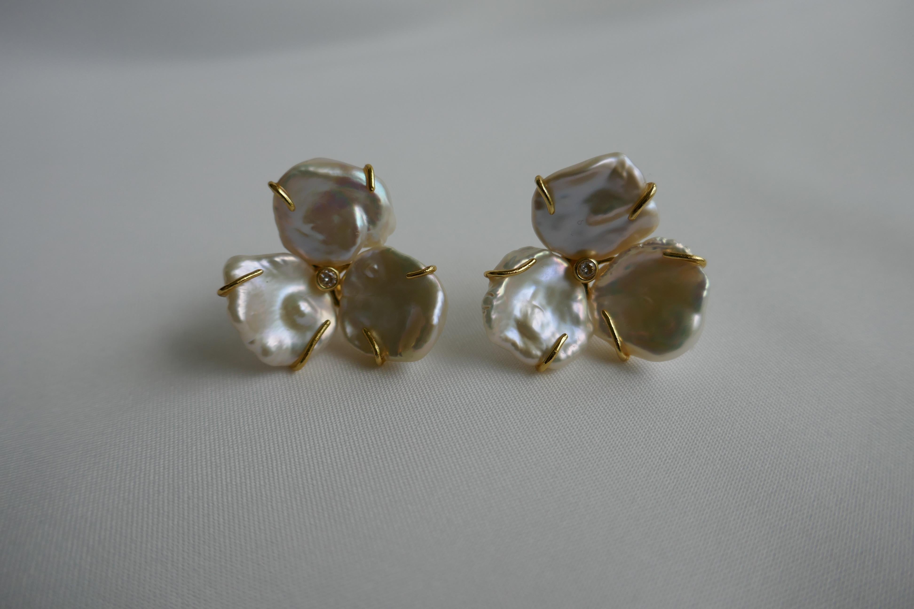 Love these earrings. Wear then for going out or casually with jeans. The earrings are made of keshi pearls made into the form of a flower on sterling silver vermeil with an omega clasp. The center stone is a cubic zirconia. The circumference of the