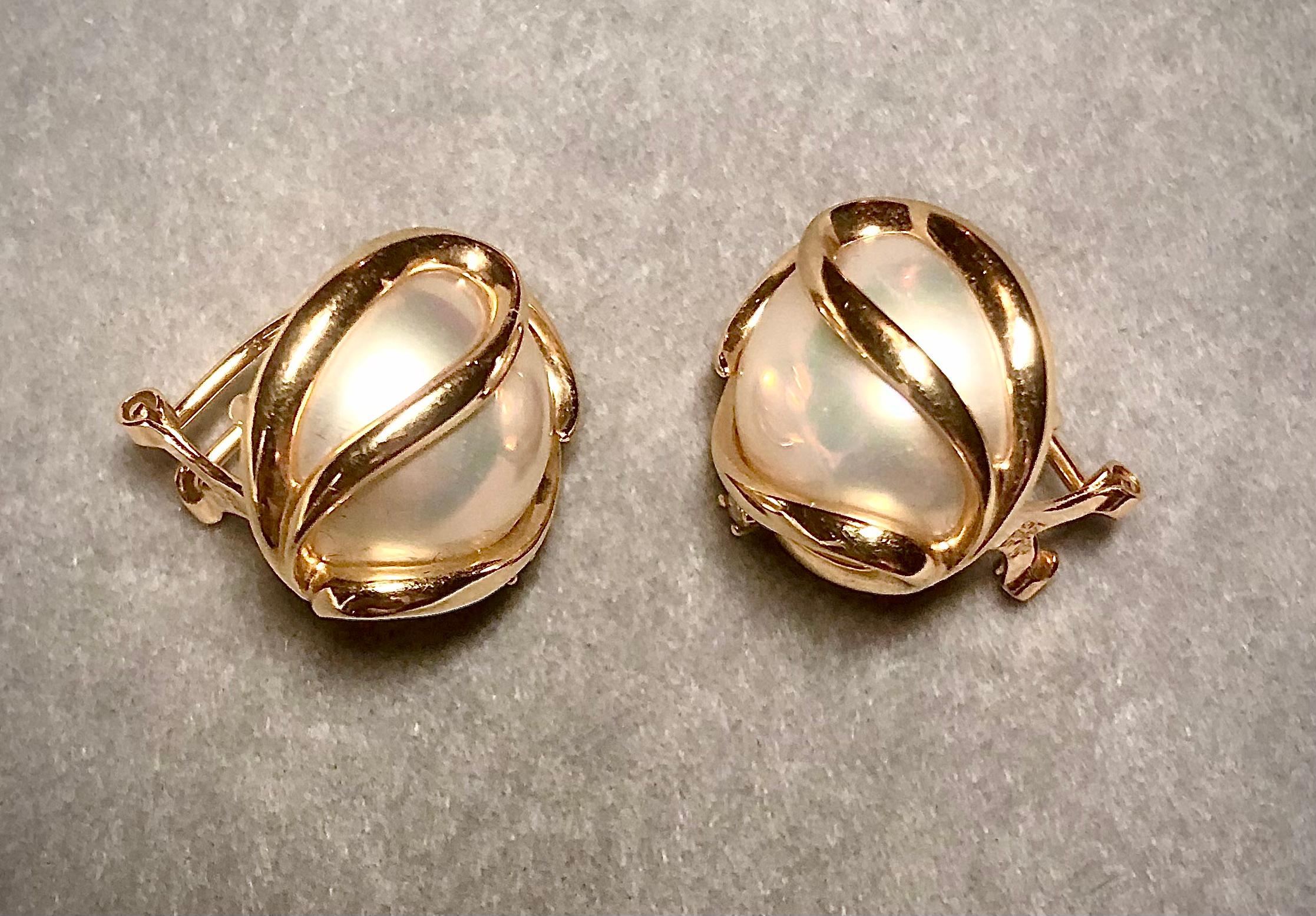 Subtle but very sophisticated design for classic cultured Mabe pearl earrings. Pearls are encased in an elegant 14kt yellow gold swirling setting accented with a small brilliant white diamond. They are secured with a substantial clip.

They are