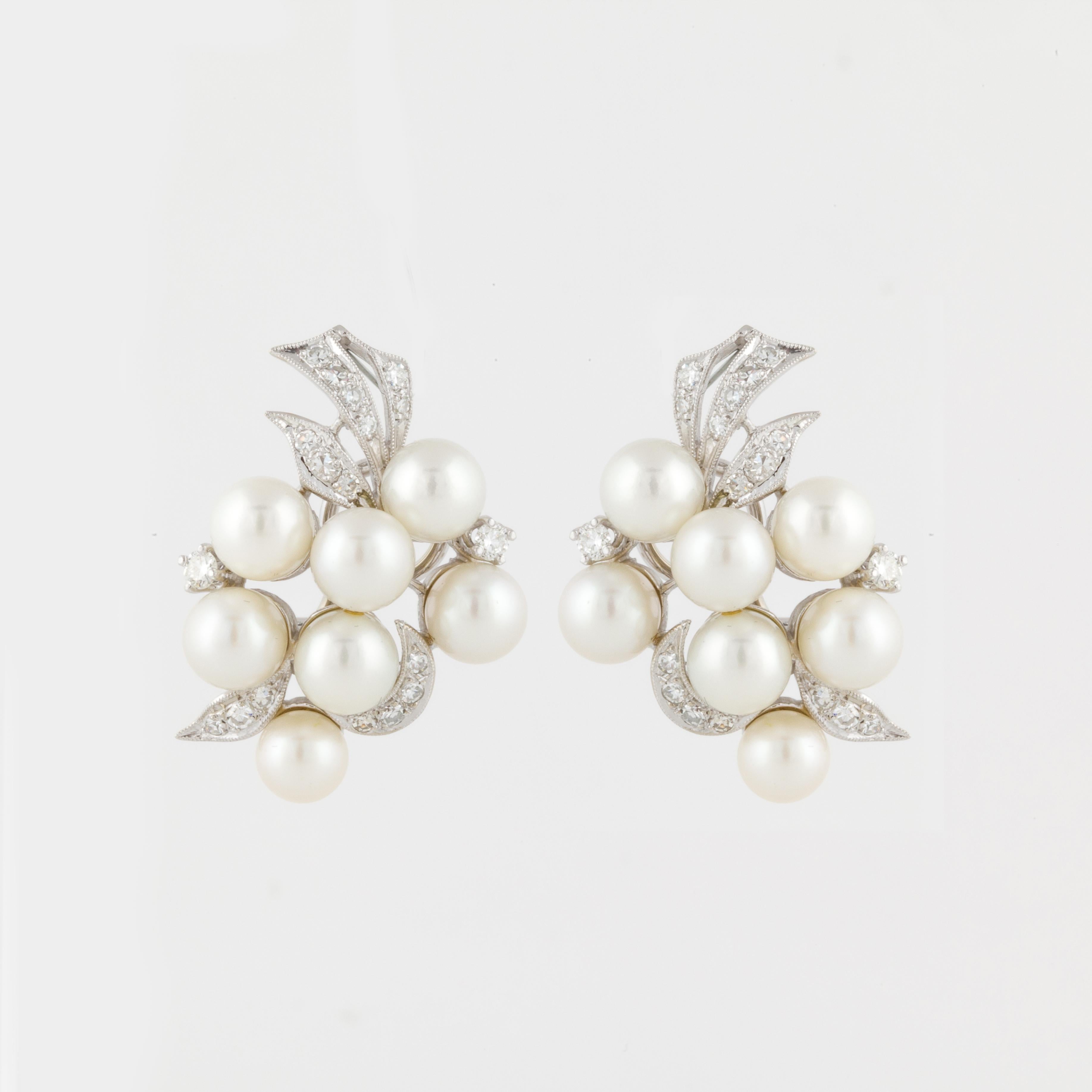 Pair of cluster earrings with cultured pearls and diamonds in 14K white gold.  There are fourteen (14) cultured pearls with thirty-six (36) diamonds that total 0.60 carats.  They measure 1 1/4 inches long and 1 inch wide. These earrings are a clip