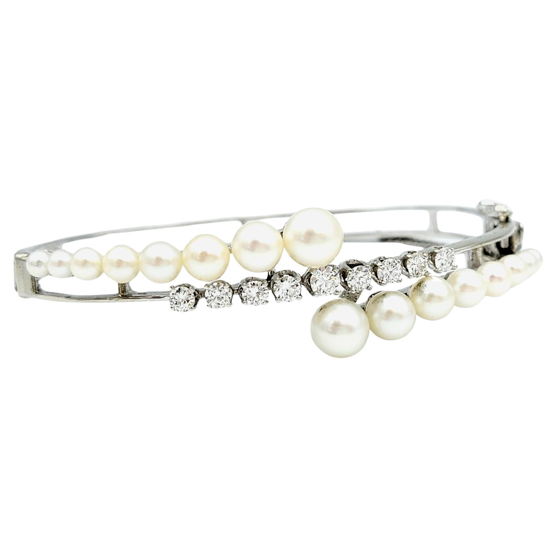 This 14 karat white gold hinged bangle bracelet is a true work of art, seamlessly blending classic elegance with modern design elements. The focus of this exquisite bracelet features an open framework of pearls and diamonds in a captivating