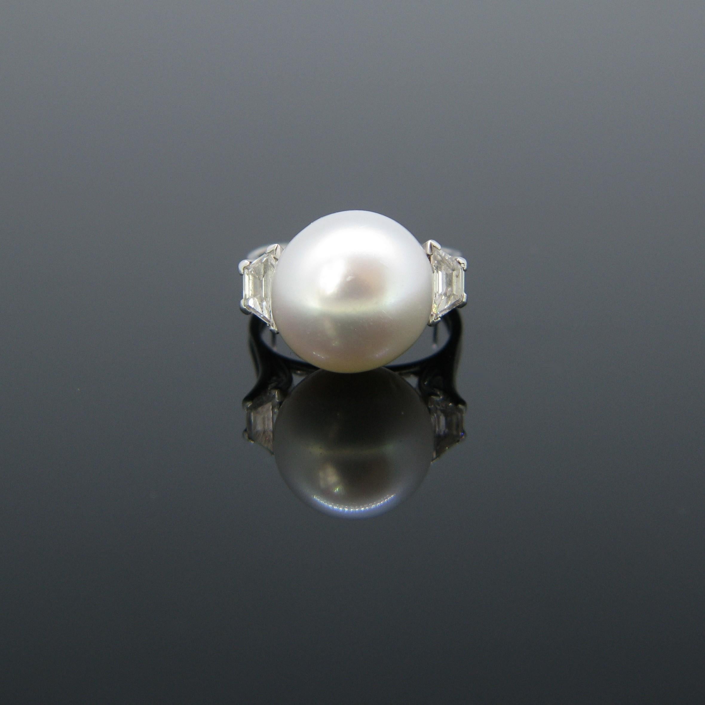 This pretty ring is made in 18kt white gold and platinum. It is set with an important white cultured pearl with pink undertones. On both sides, are two trapeze diamonds weighing 0.15ct approximately. It is a very beautiful ring.

Weight: