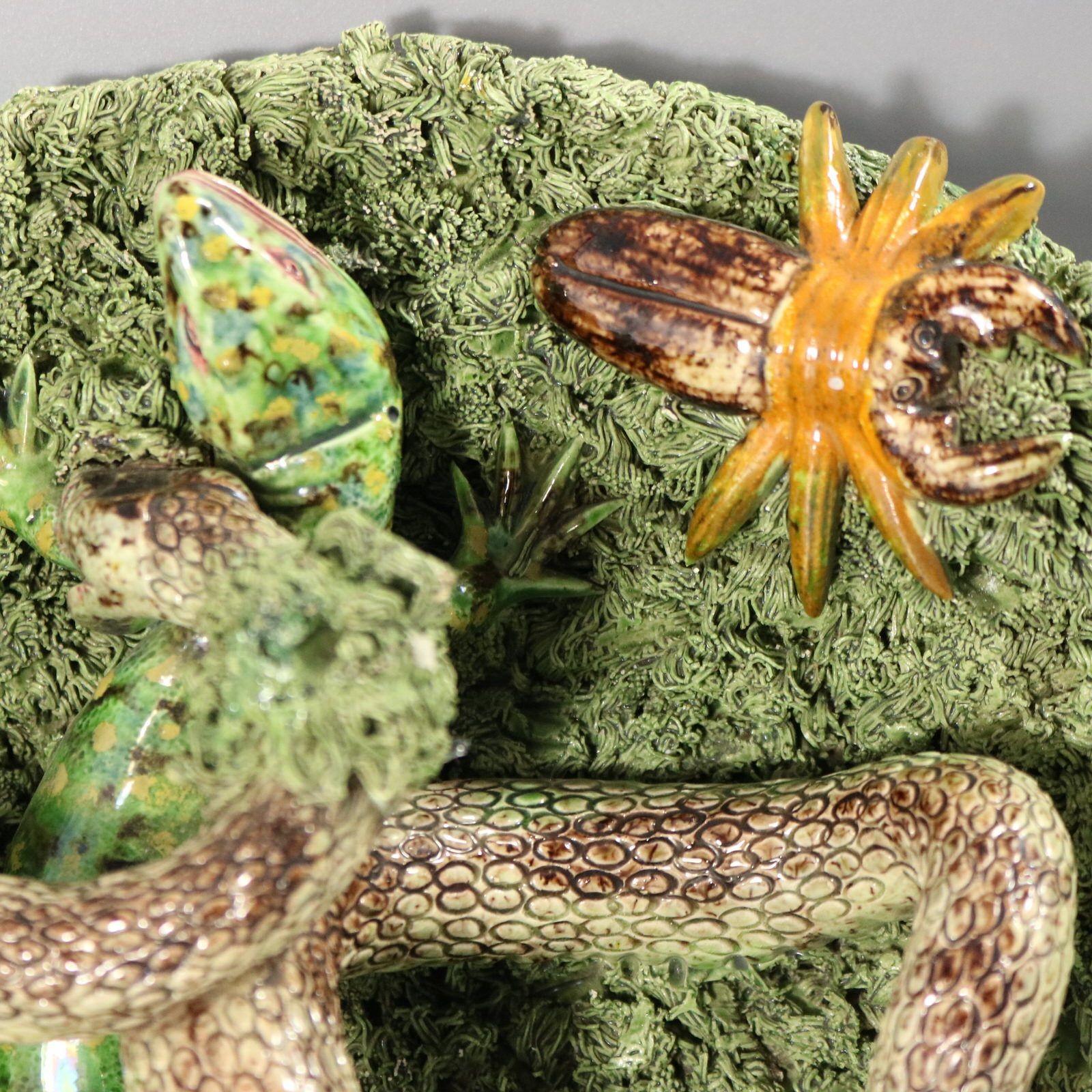 Jose A Cunha Portuguese Palissy Majolica wall plate which features a snake attacking a lizard. Insects around the outside of the plate include a grub, a worm, a butterfly and a beetle. Colouration: green, grey, brown, are predominant. The piece