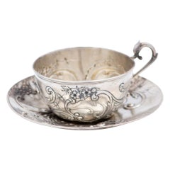 Cup and saucer in embossed silver with floral motifs and garlands